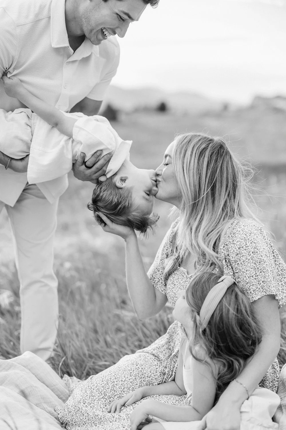 Black-and-white candid portrait of parents playing with their children outdoors in Colorado.