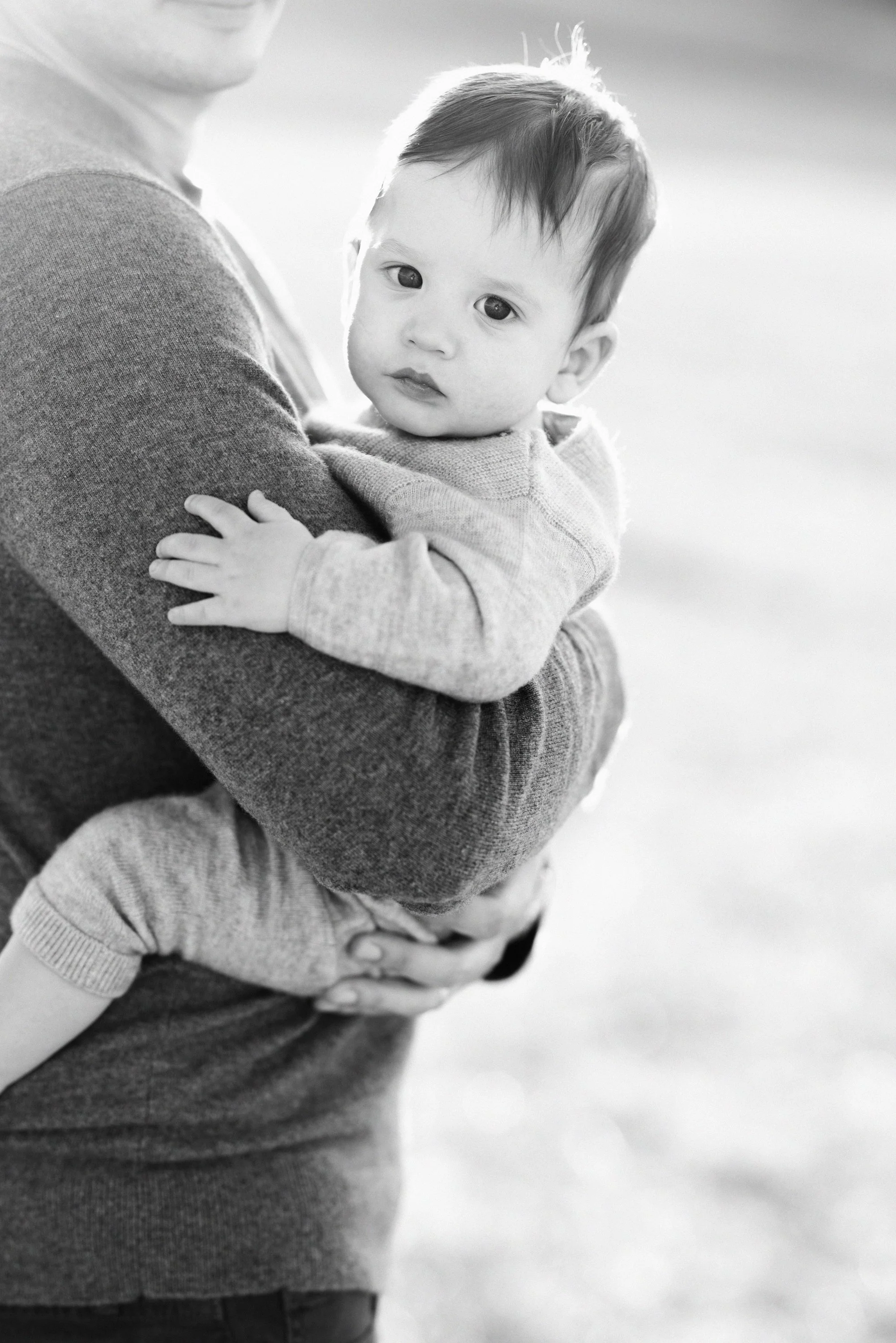 Baby resting against her father in an intimate black and white family portrait.