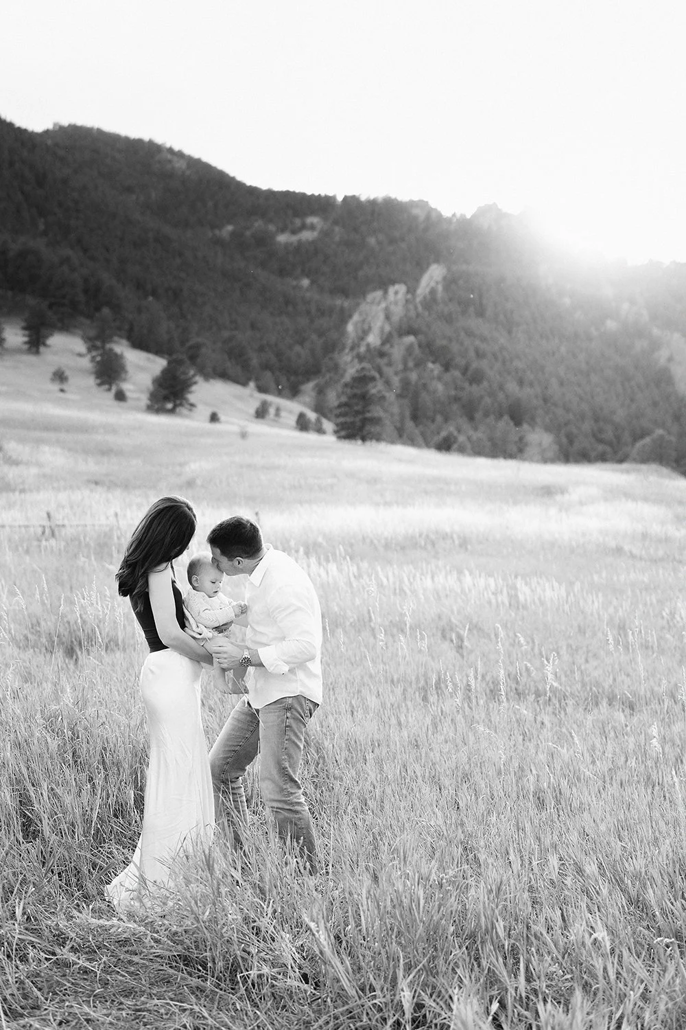 Black and white photograph of a parent and child playing together in a Colorado field at sunset