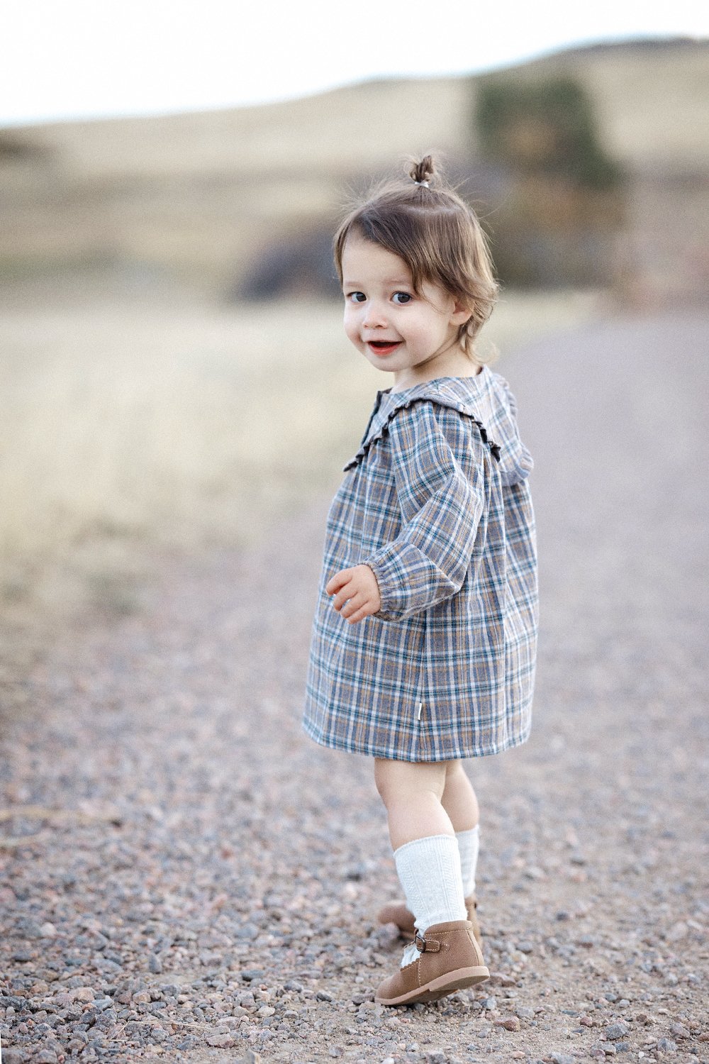 Child walking on gravel path looking back to camera during family portrait