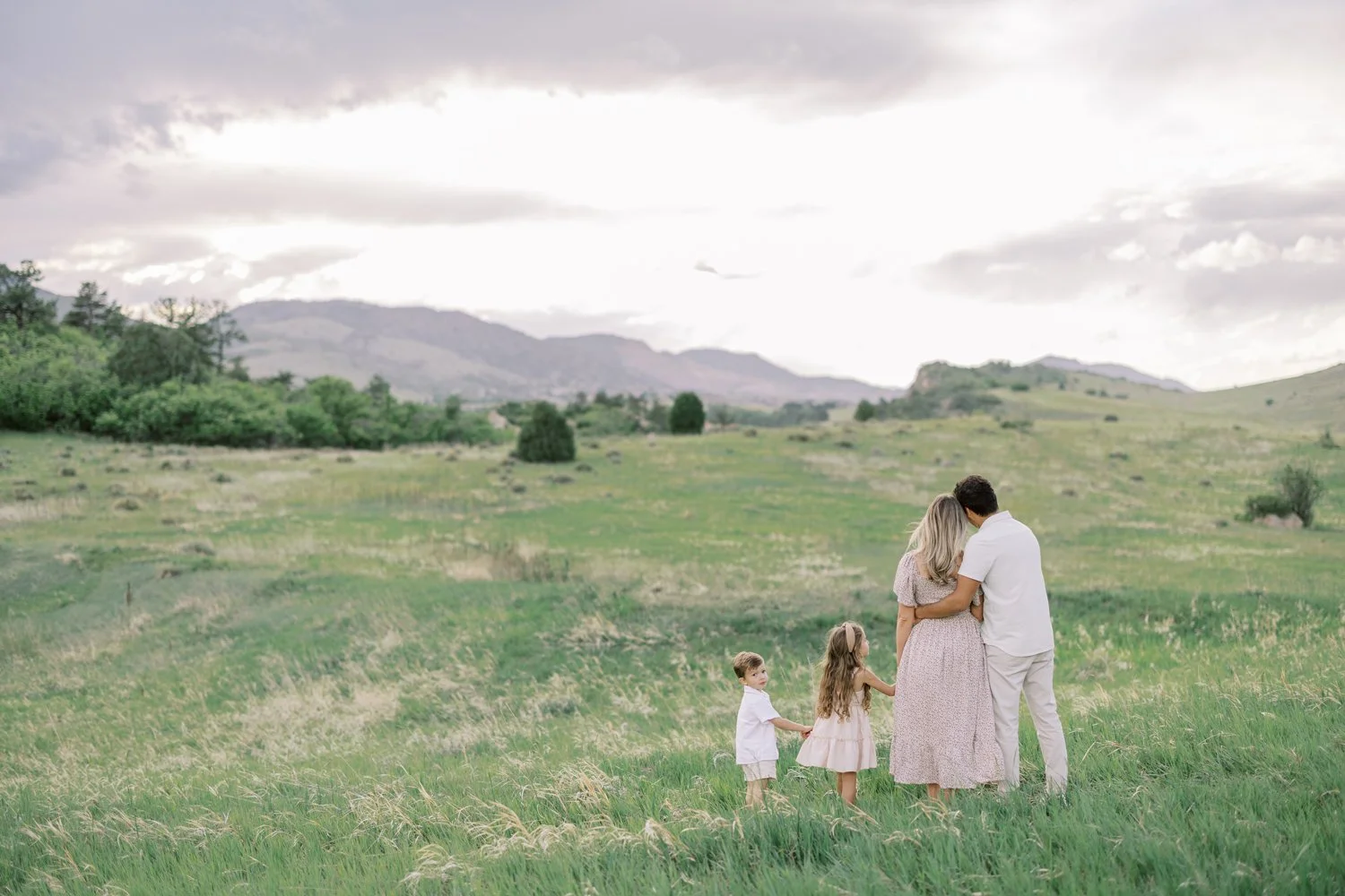 Family walking together in a green field with mountains in distance
