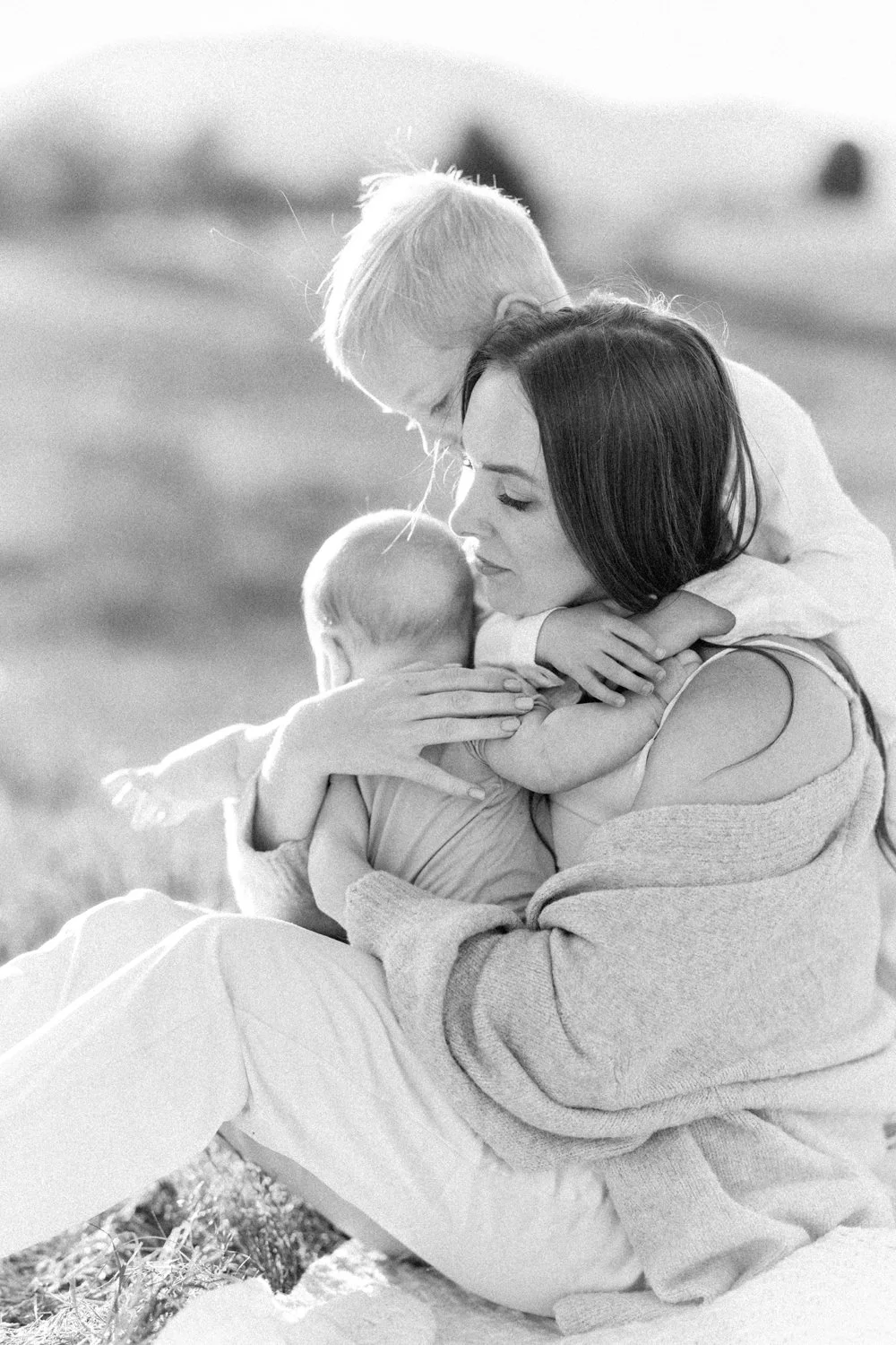 mom and young sons snuggling together during family portrait