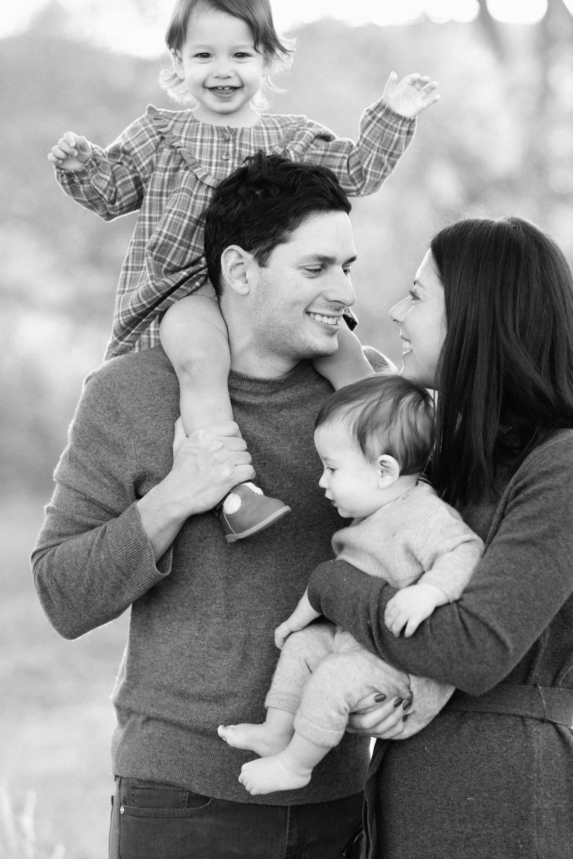 Parents holding their two children during a playful black and white Denver family portrait.