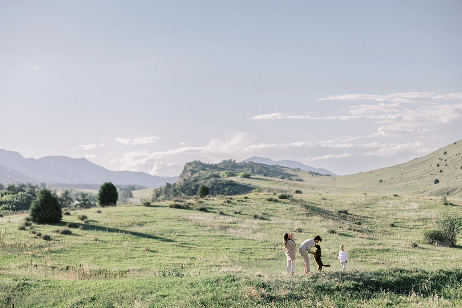 Family and dog walking through hills in Colorado mountain area