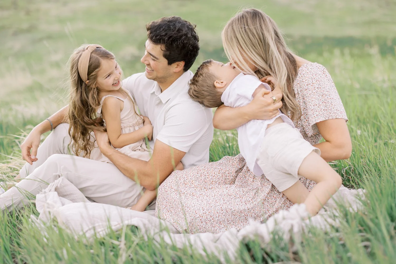 Family sitting closely together in a grassy Colorado field.