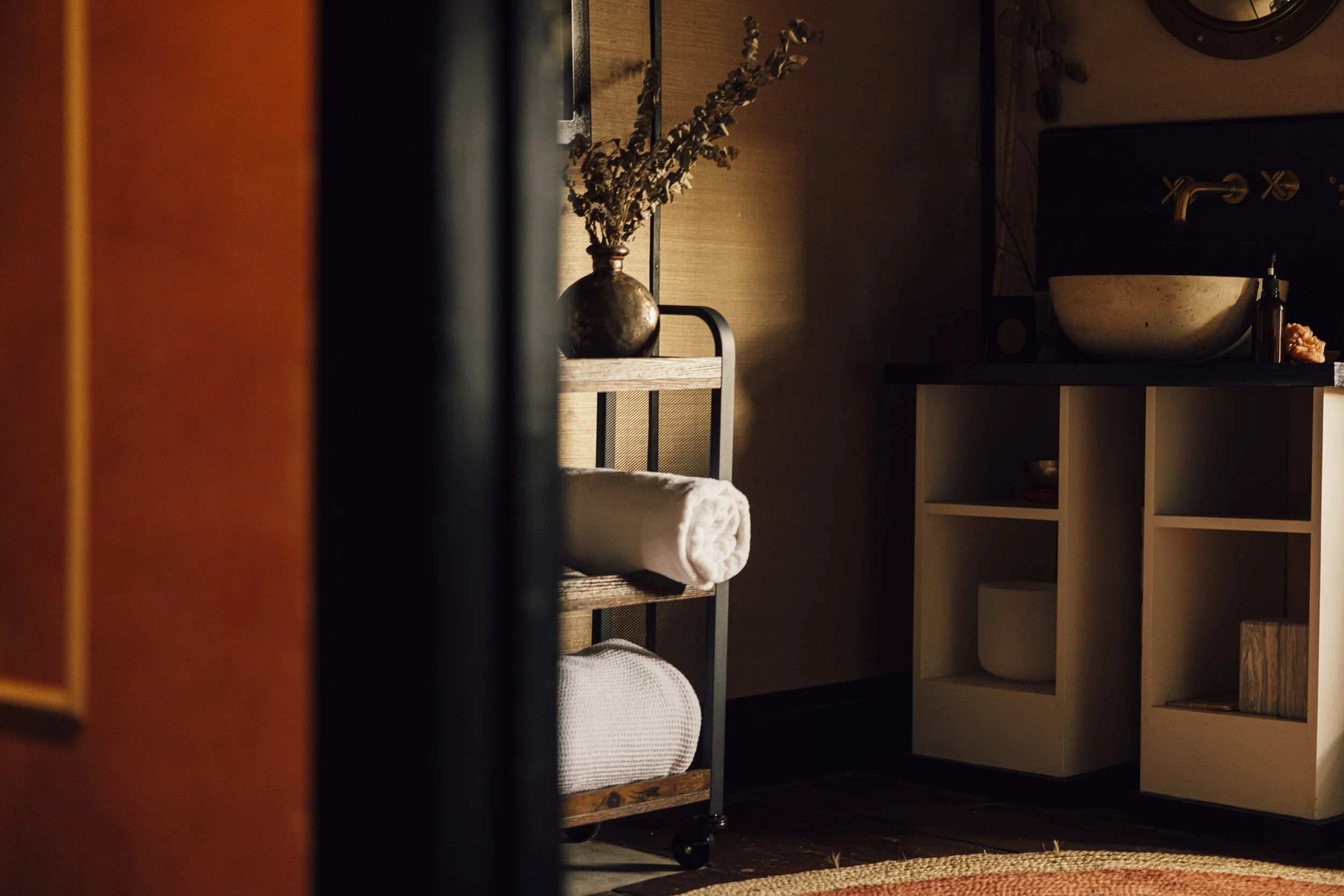 Cozy bathroom with rolled towels, decorative vase, and modern sink on a countertop.