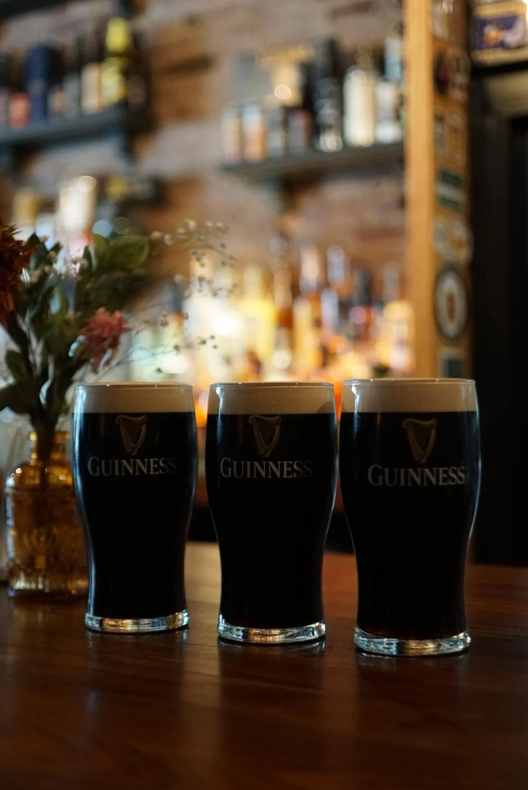 three pints of side poured Guinness sitting on the bar at Queue Beer