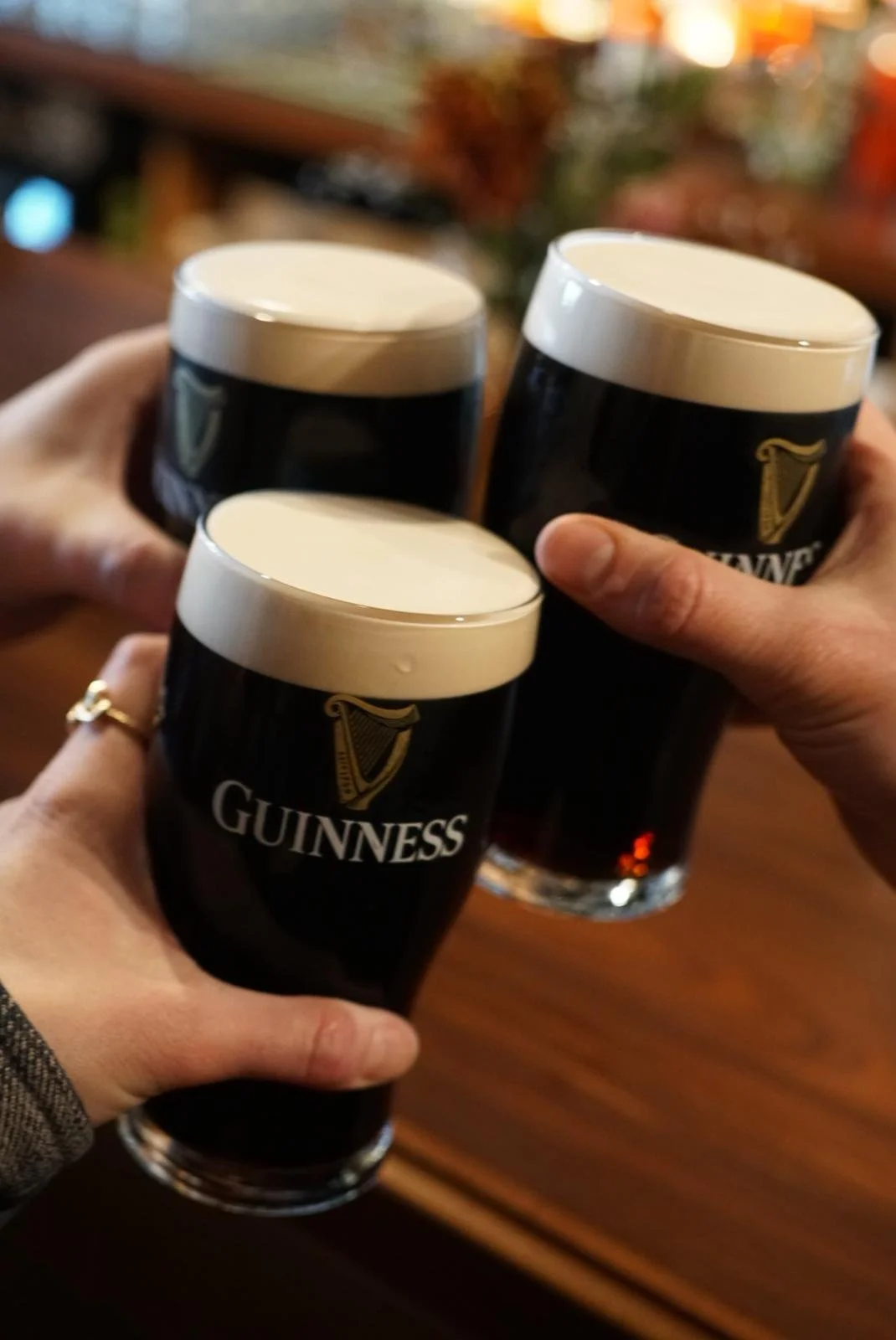 three pints of side-poured Guinness arranged to cheers