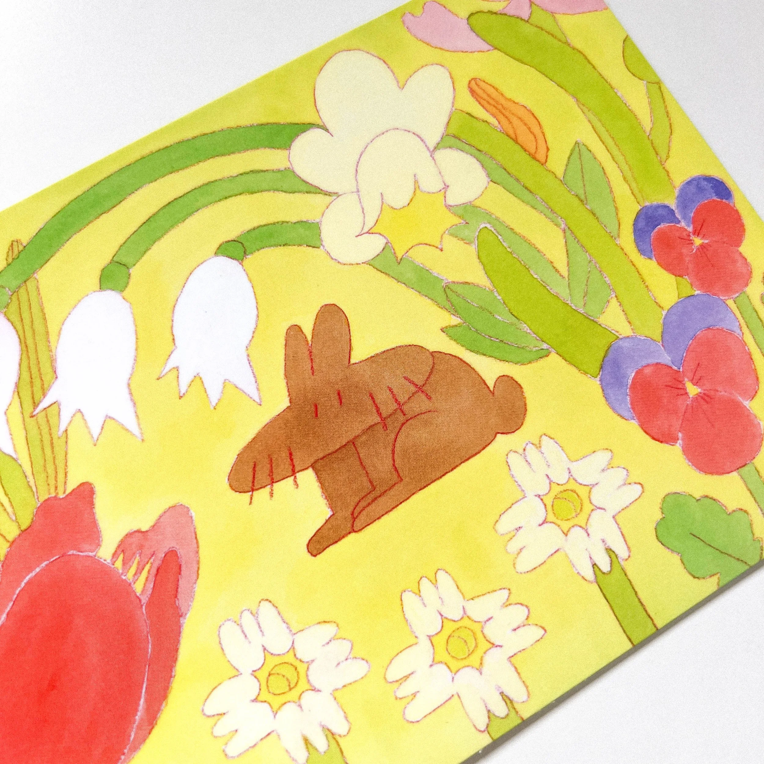 Single A6 card from “The Blooming Spring Realm” bundle with a soft yellow background. A brown rabbit sits among blooming spring flowers like pansies, daffodils, and snowdrops in a nature setting.
