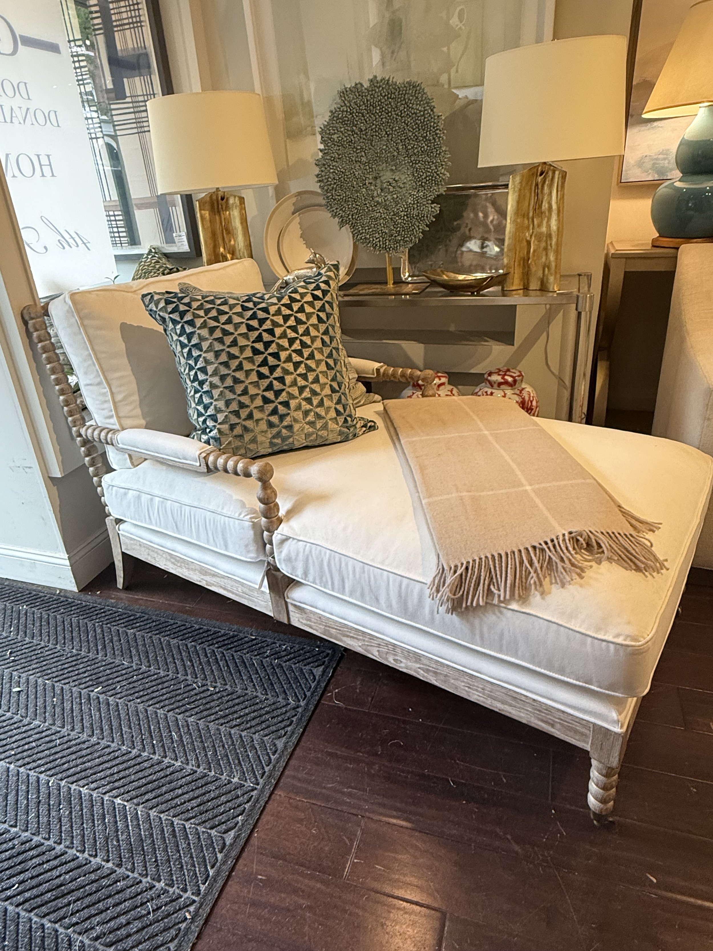 Spool Lounge Chair with hand-carved wood frame and ivory cushions, styled with a throw and geometric pillow, available at Donna Donaldson Interiors.