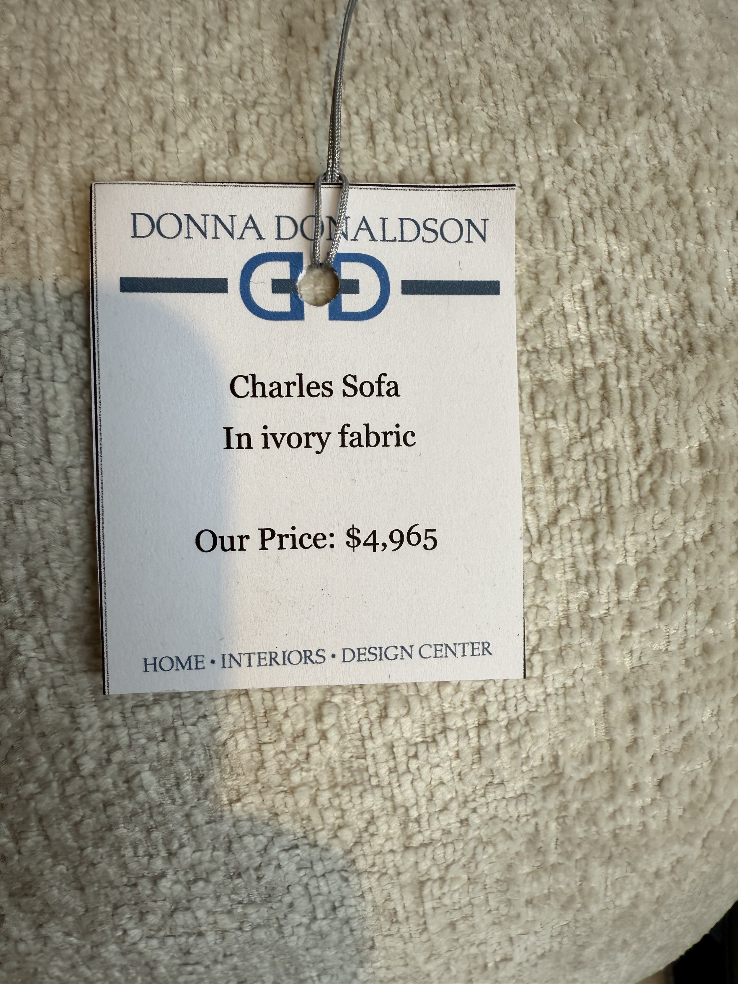 Price tag- $4965 Charles Sofa in ivory fabric with plush cushions, nailhead trim, and green accent pillows, available at Donna Donaldson Interiors.