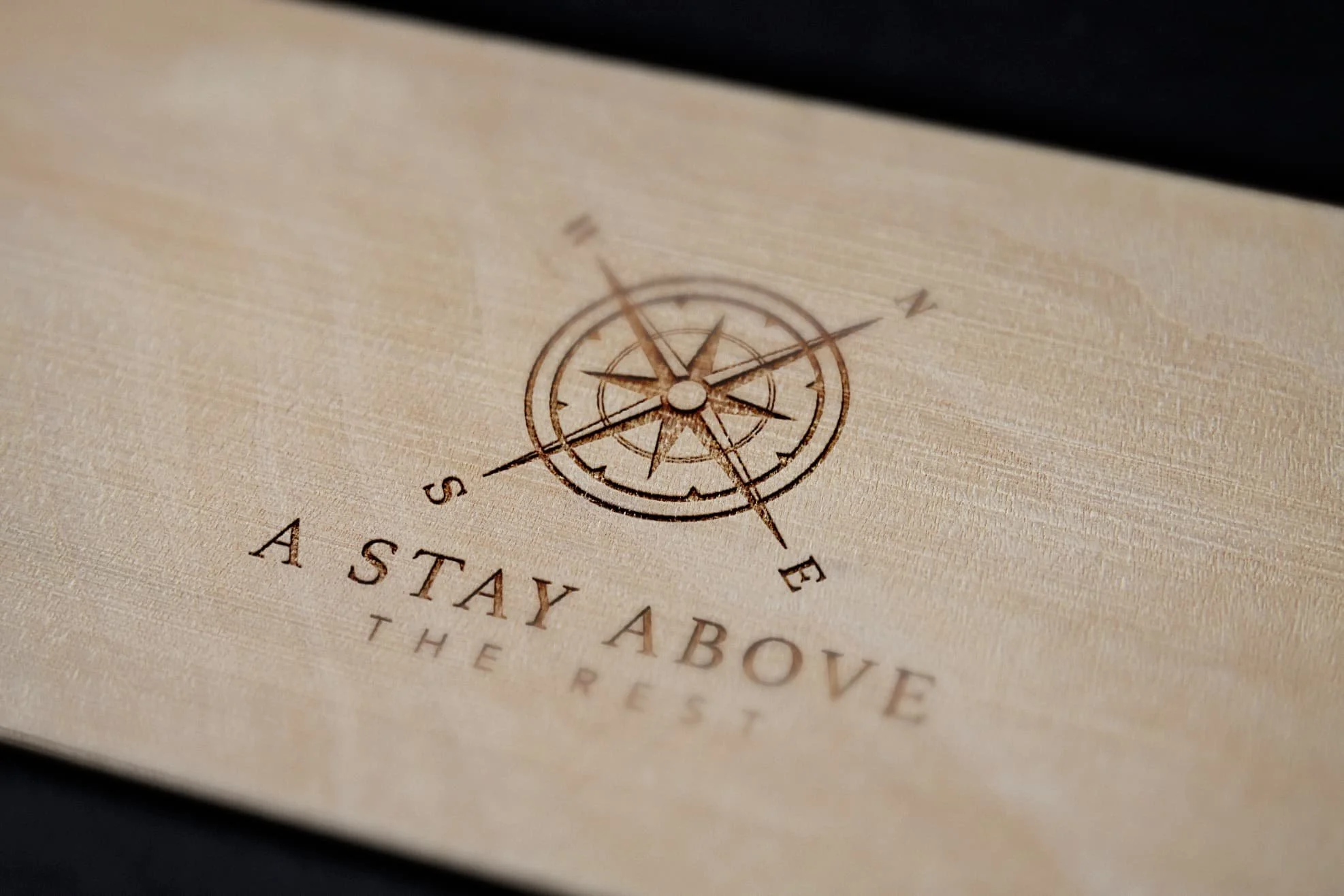 Wooden surface with a compass design engraved on it. Below the compass, the words "A Stay Above The Rest" are engraved.