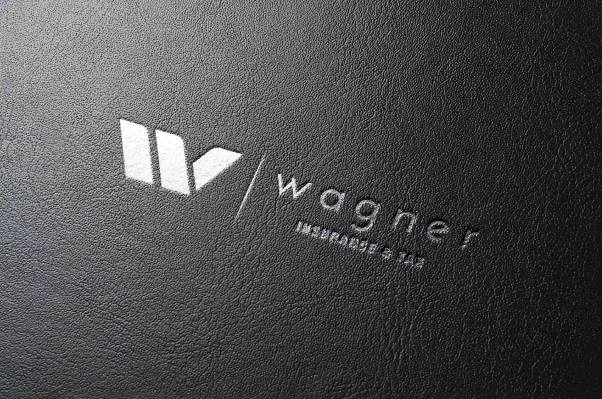 Close-up of a black textured surface with a silver embossed logo reading "Wagner" and a stylized icon.