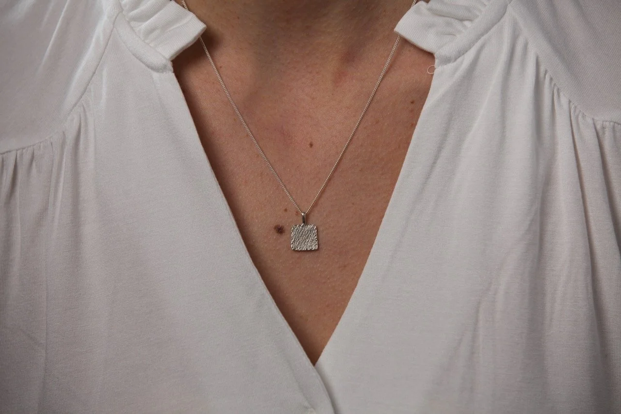 close-up-shot-of-model-wearing-a-white-blouse-and-square-pendant-necklace.jpeg