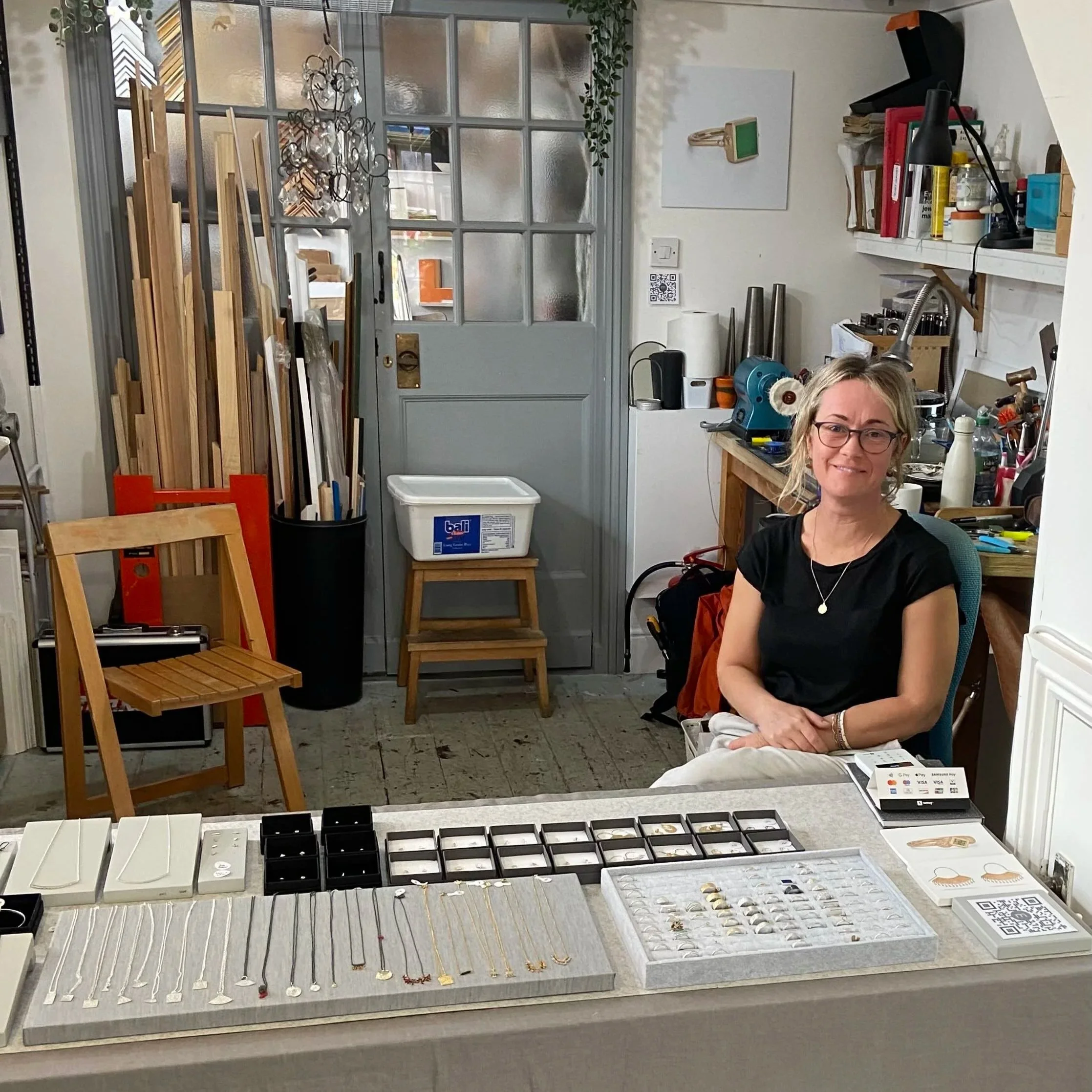 Mim Best sat in her workshop behind a table with her seconds offerings laid out on top
