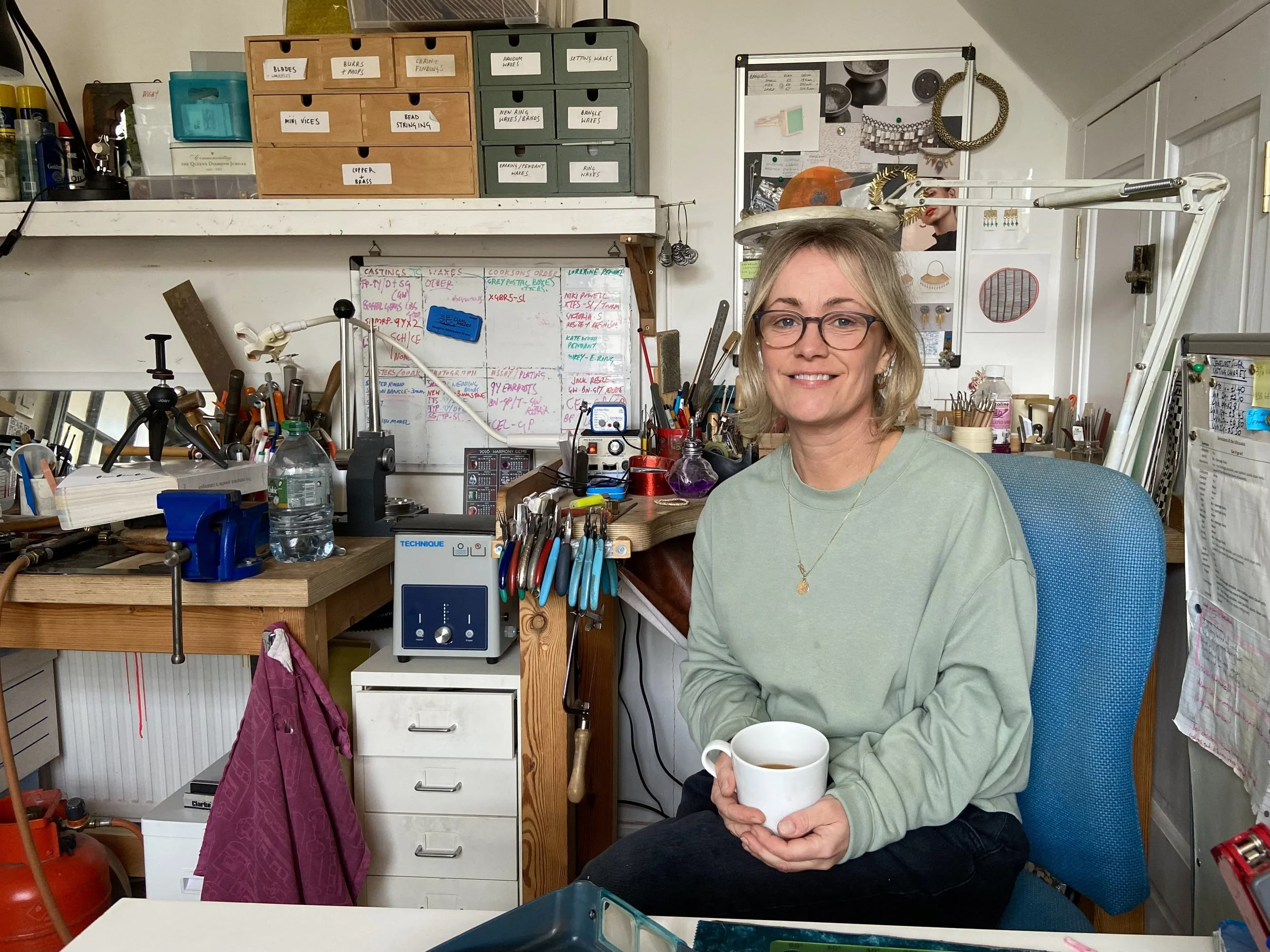 Mim Best holding a mug sat at her workshop desk