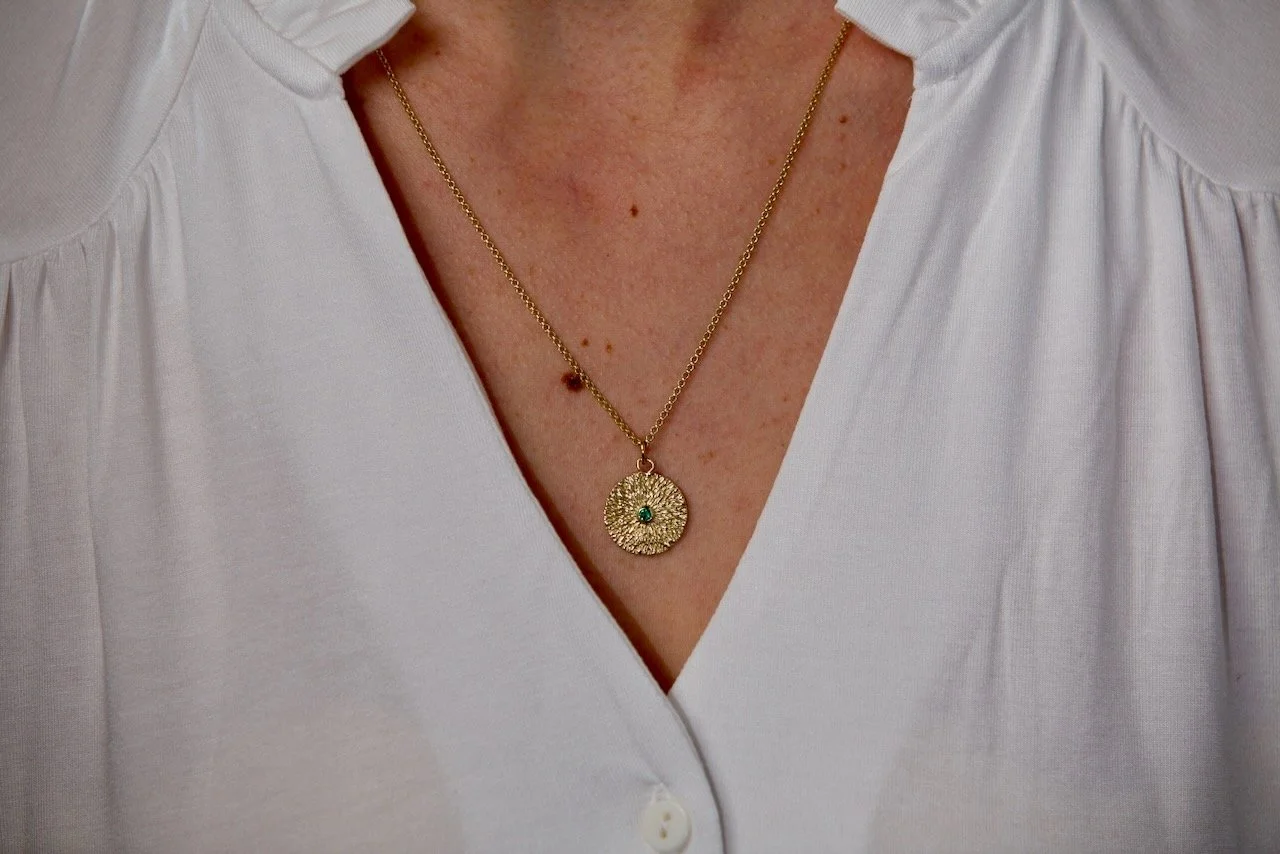 close-up-shot-of-models-chest-wearing-a-handmade-gold-starburst-pendant-necklace.jpeg