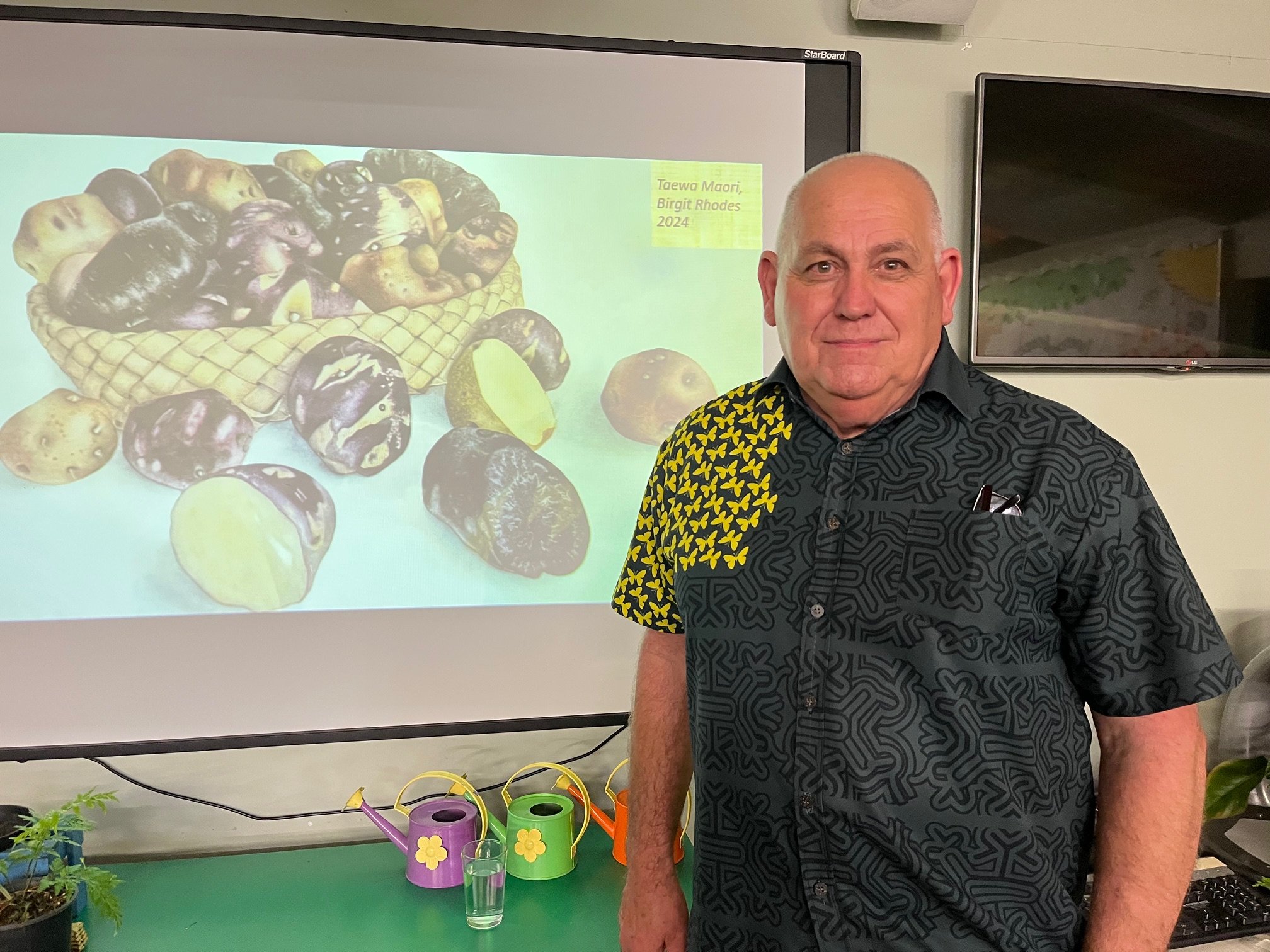De Nick Roskruge with Birgit Rhode's artwork of Maori potatoes on his presentation