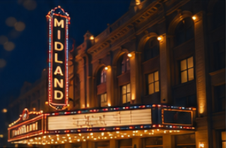 The Midland theater marquee at night with bright lights and an illuminated vertical sign displaying 'MIDLAND'.