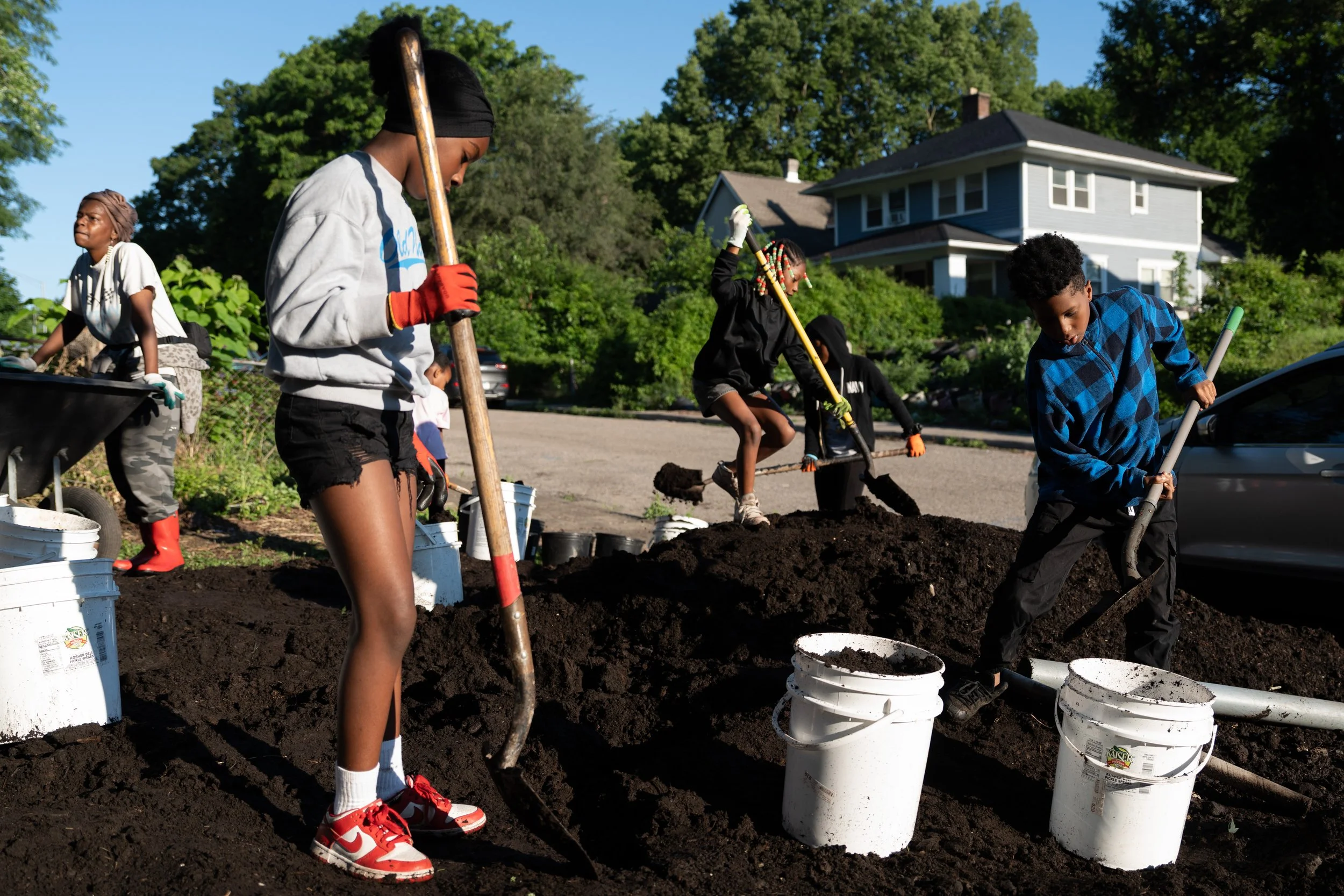 Kids fill buckets with soil at Mother Loves Garden, a summer camp where kids are paid to learn how to garden on June 23, 2026 in Indianapolis.