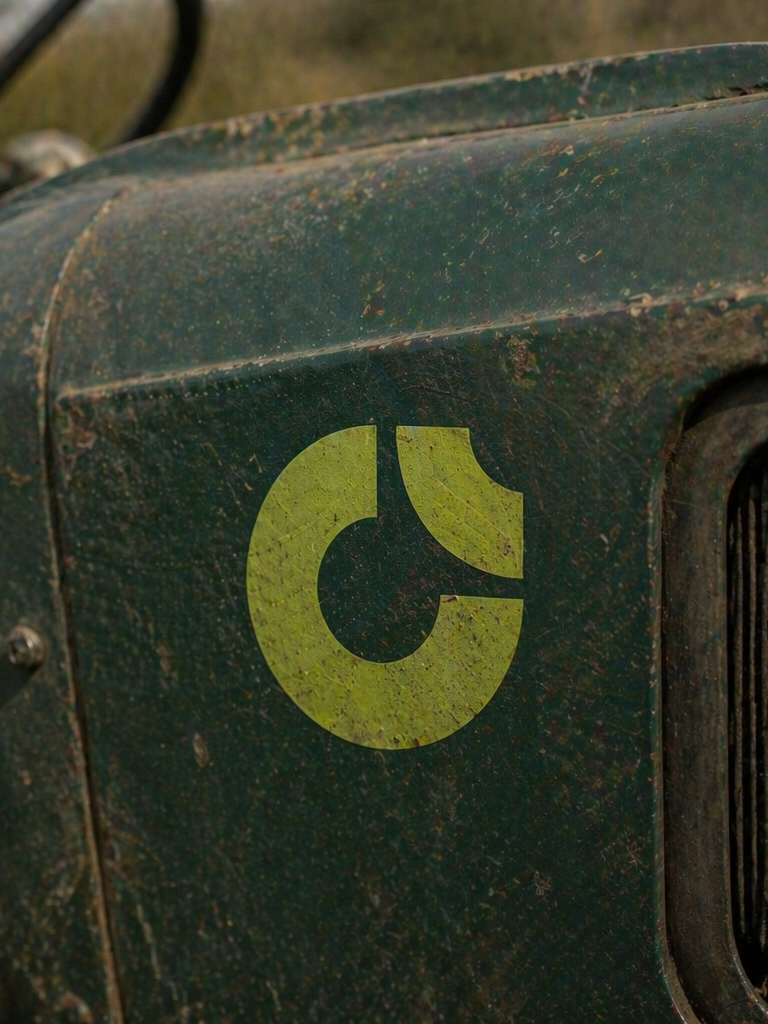Texto en una superficie metálica desgastada y cubierta de polvo y óxido, que muestra una pegatina amarilla con un diseño circular y una línea que simula una ruptura.