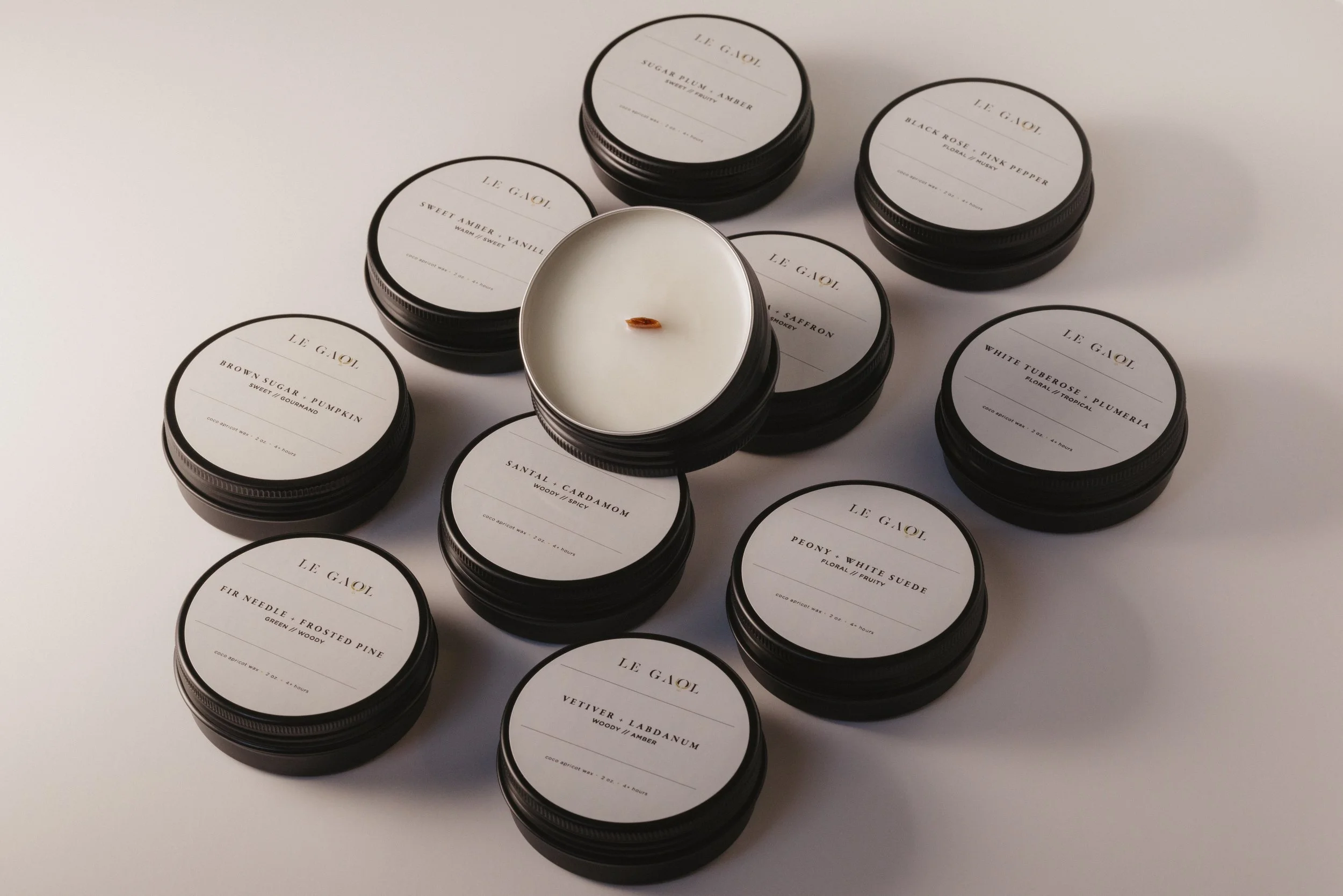Le Gaol discovery candle collection in black tins, featuring an assortment of fragrances and a wooden wick candle.
