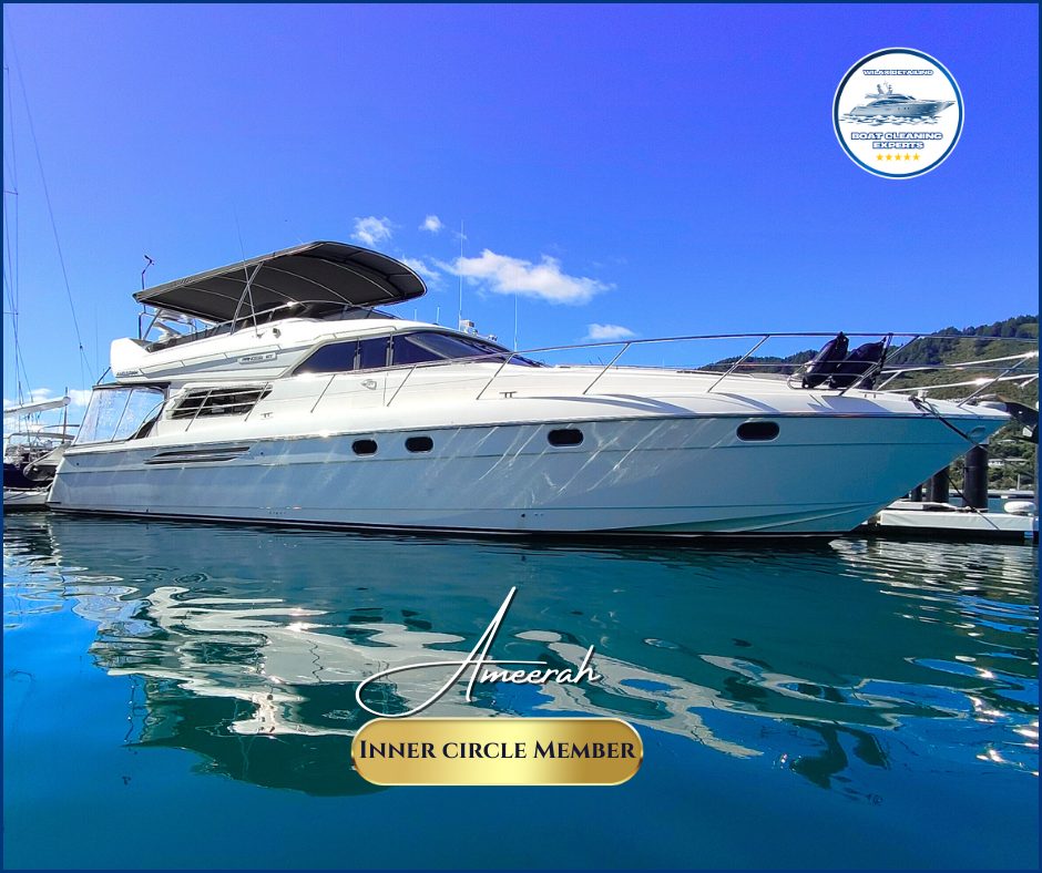 Luxury yacht docked in a marina with mountains in the background under a clear blue sky.