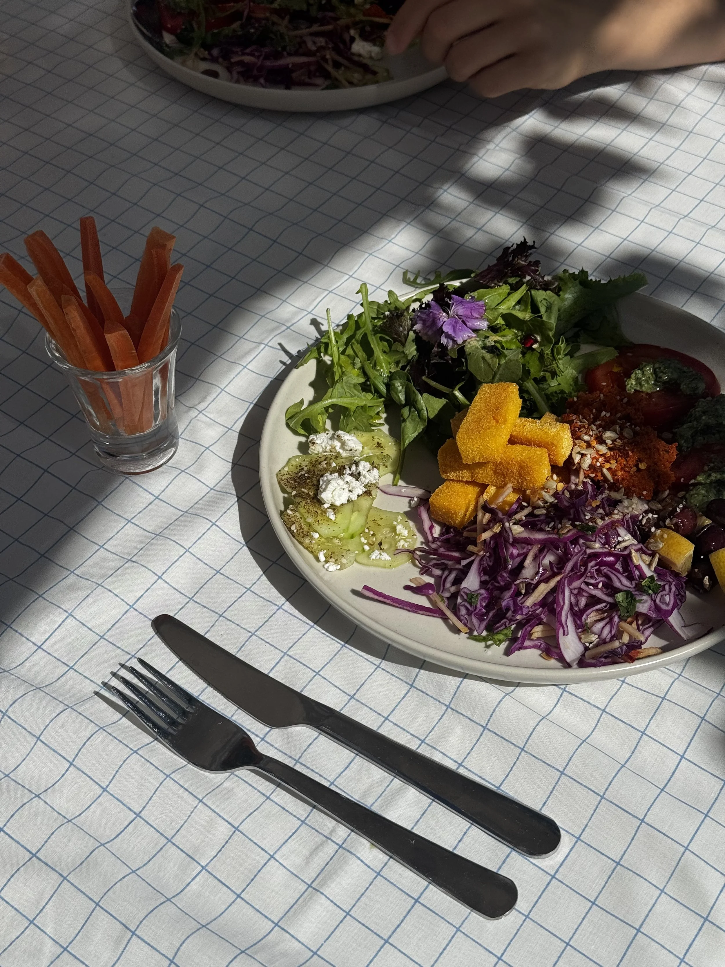 Fresh mixed salad on a white plate with shredded purple cabbage, sliced cucumbers, orange croutons, cherry tomatoes, greens, and cheese for a healthy yoga retreat meal in Portugal