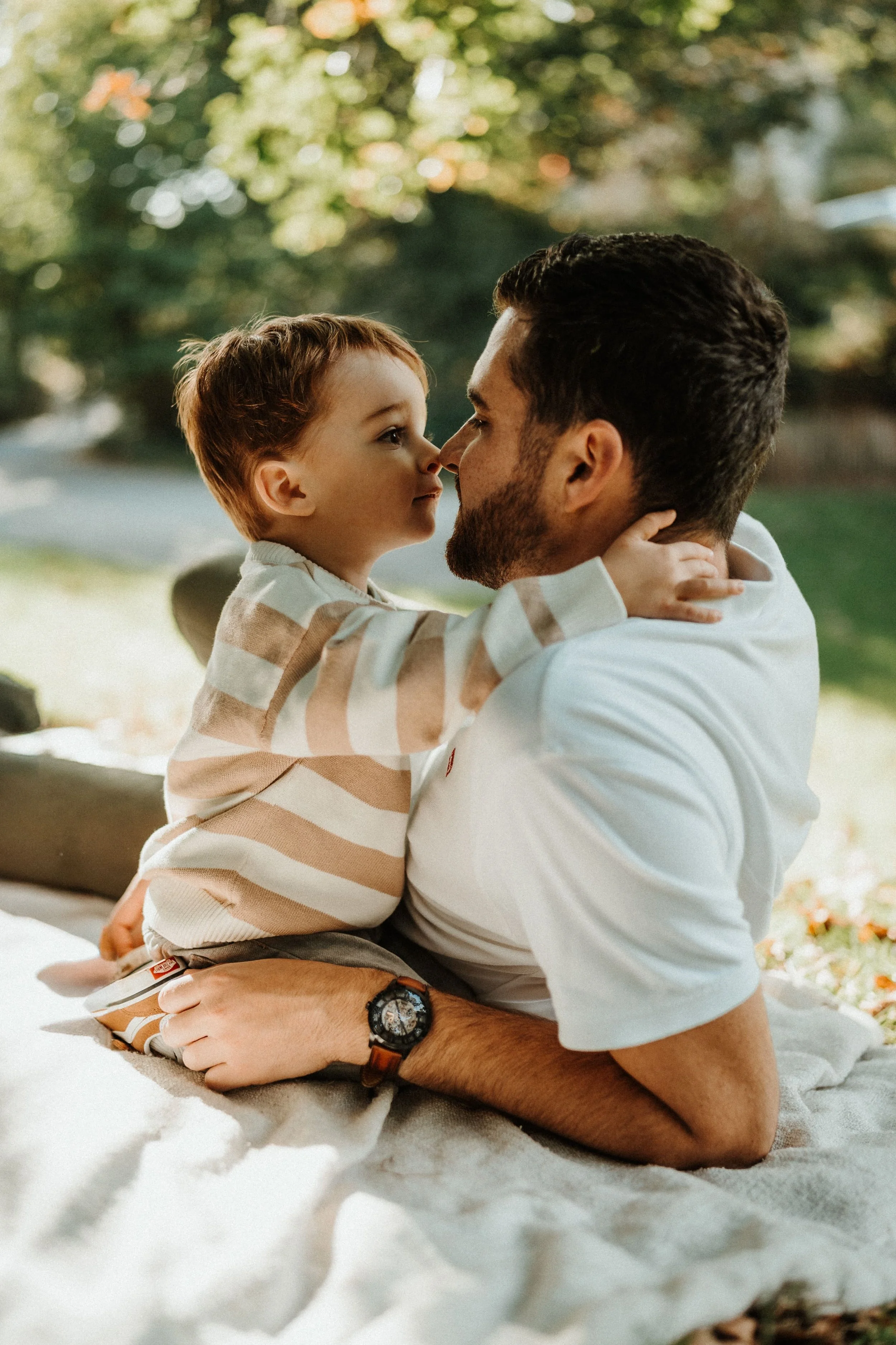 Photo de famille naturelle, papa et son enfant en moment de complicité dans un parc en Bretagne
