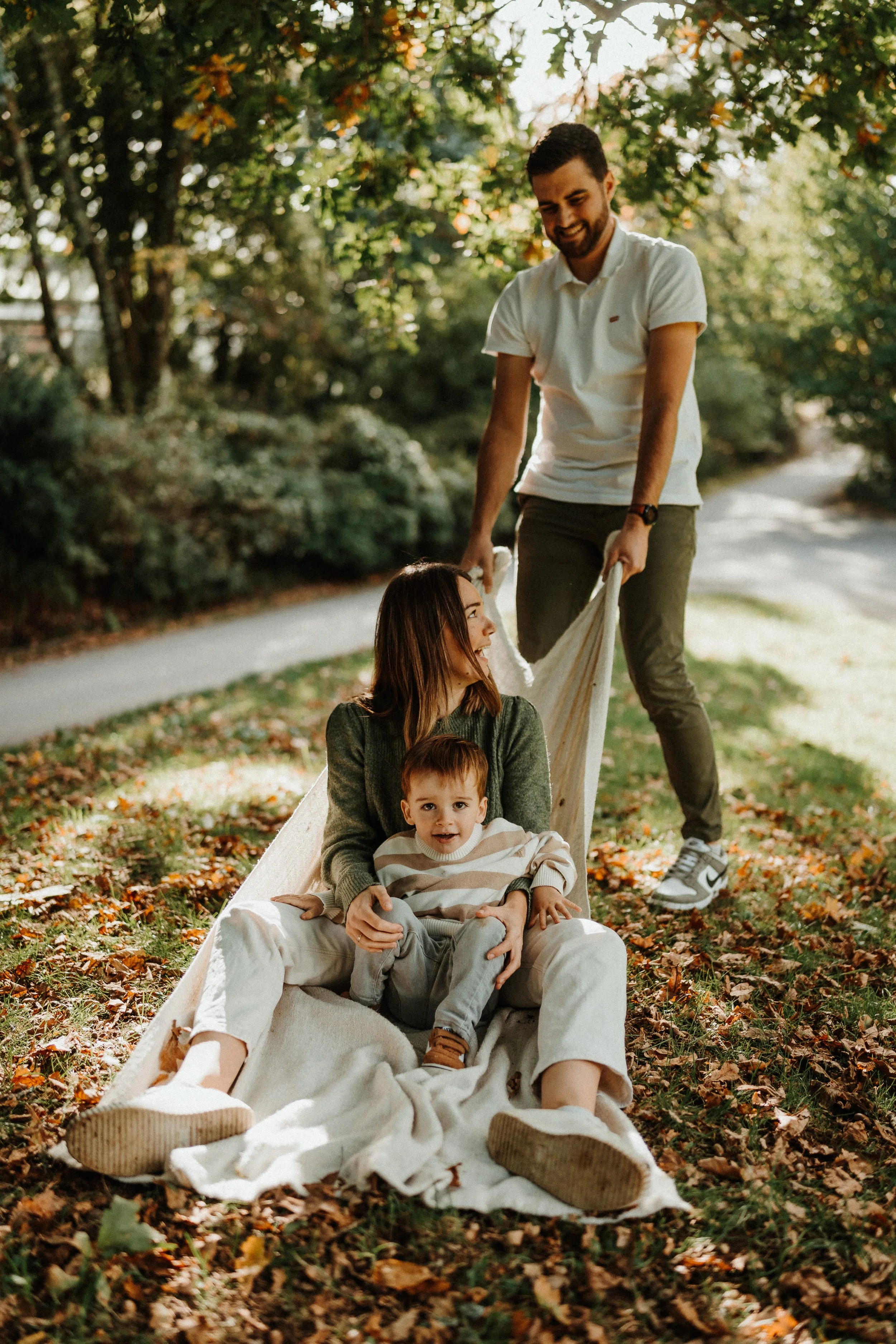 Séance photo famille lifestyle en extérieur, parents et enfant qui jouent sur un plaid en Bretagne