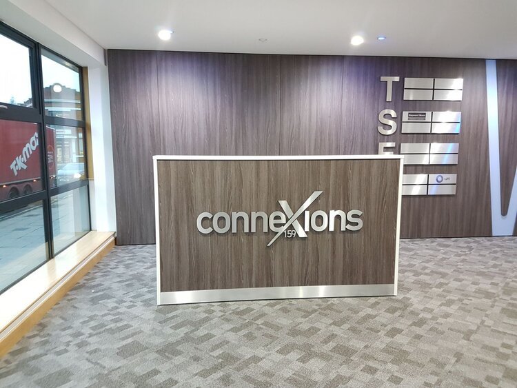 Silver Connexion stud fixed sign on a wood effect wall