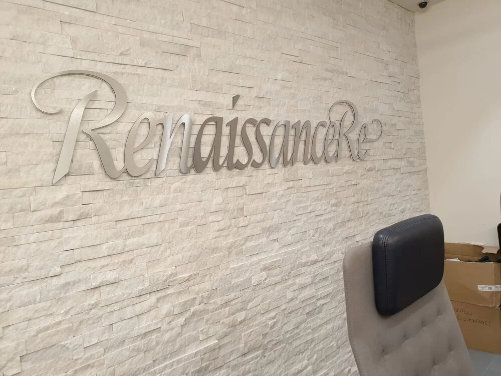 Silver letter logo on a white brick wall