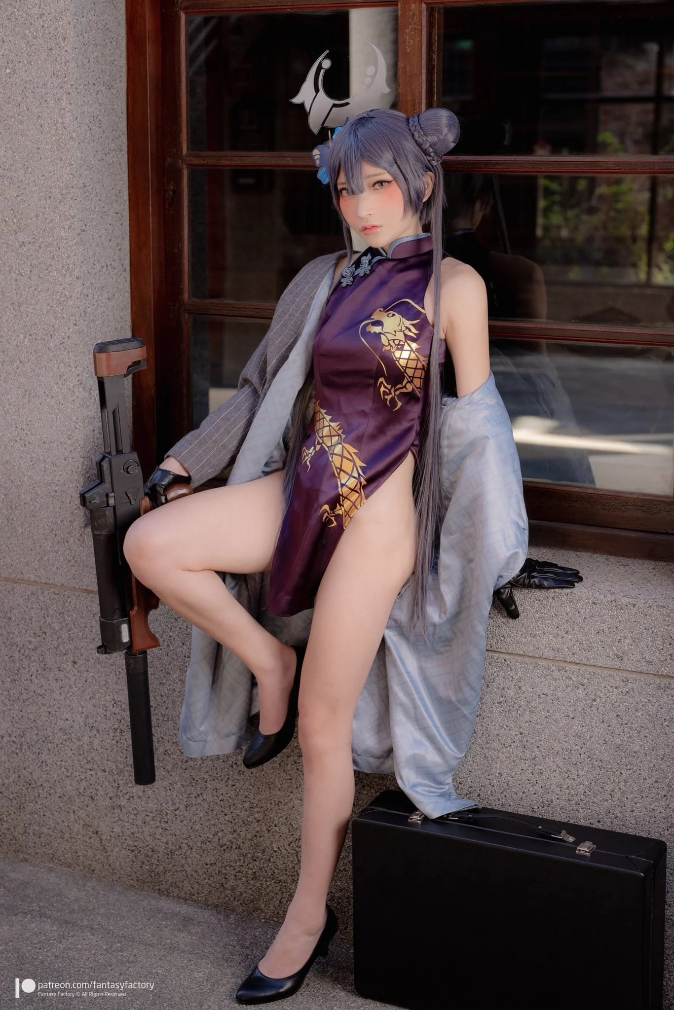 A woman in a detailed cosplay costume with a purple dress featuring a gold dragon, black heels, a gray coat, and holding a pistol, stands in front of a window with wooden framing. She has long dark hair styled in buns, and a black briefcase is on the