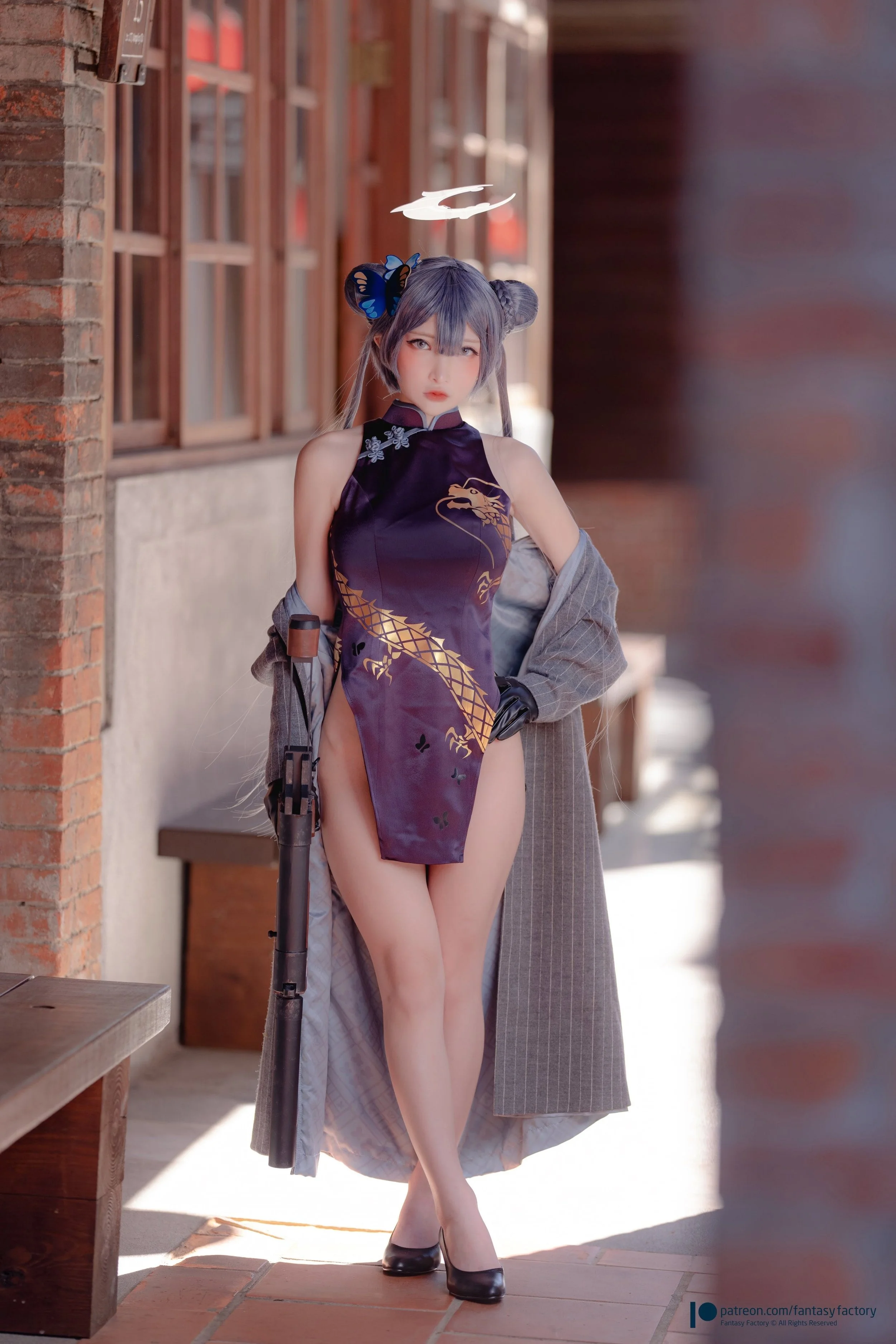 A person in cosplay, dressed as a character with a dark purple dress featuring gold dragon design, black heels, and gray hair styled in buns with butterfly hair accessories, standing outside a building with brick and wood walls.