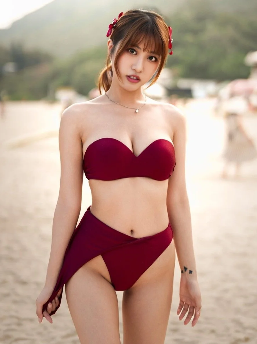 Young woman in a maroon bikini on a beach.