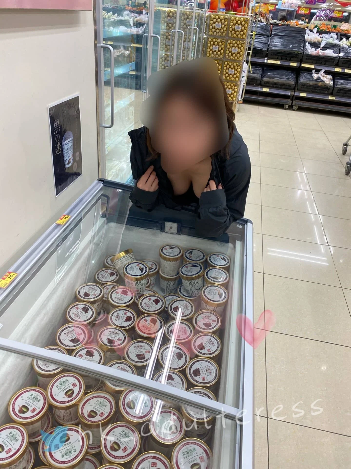 A woman leaning over a freezer in a grocery store, looking at cups of ice cream inside.