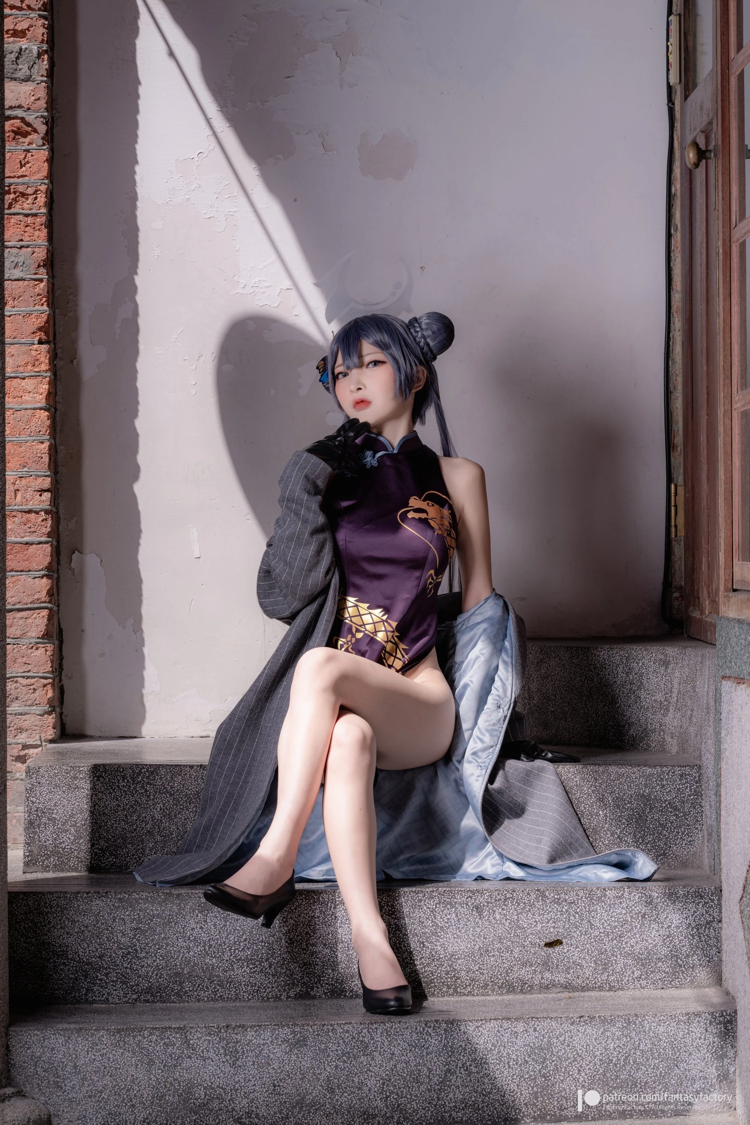 A woman with black hair styled in two buns, wearing a sleeveless purple dress with gold dragon design, black high heels, and black gloves, sitting on outdoor steps beside a partially open wooden door, with a gray coat holding her dress. The backgroun