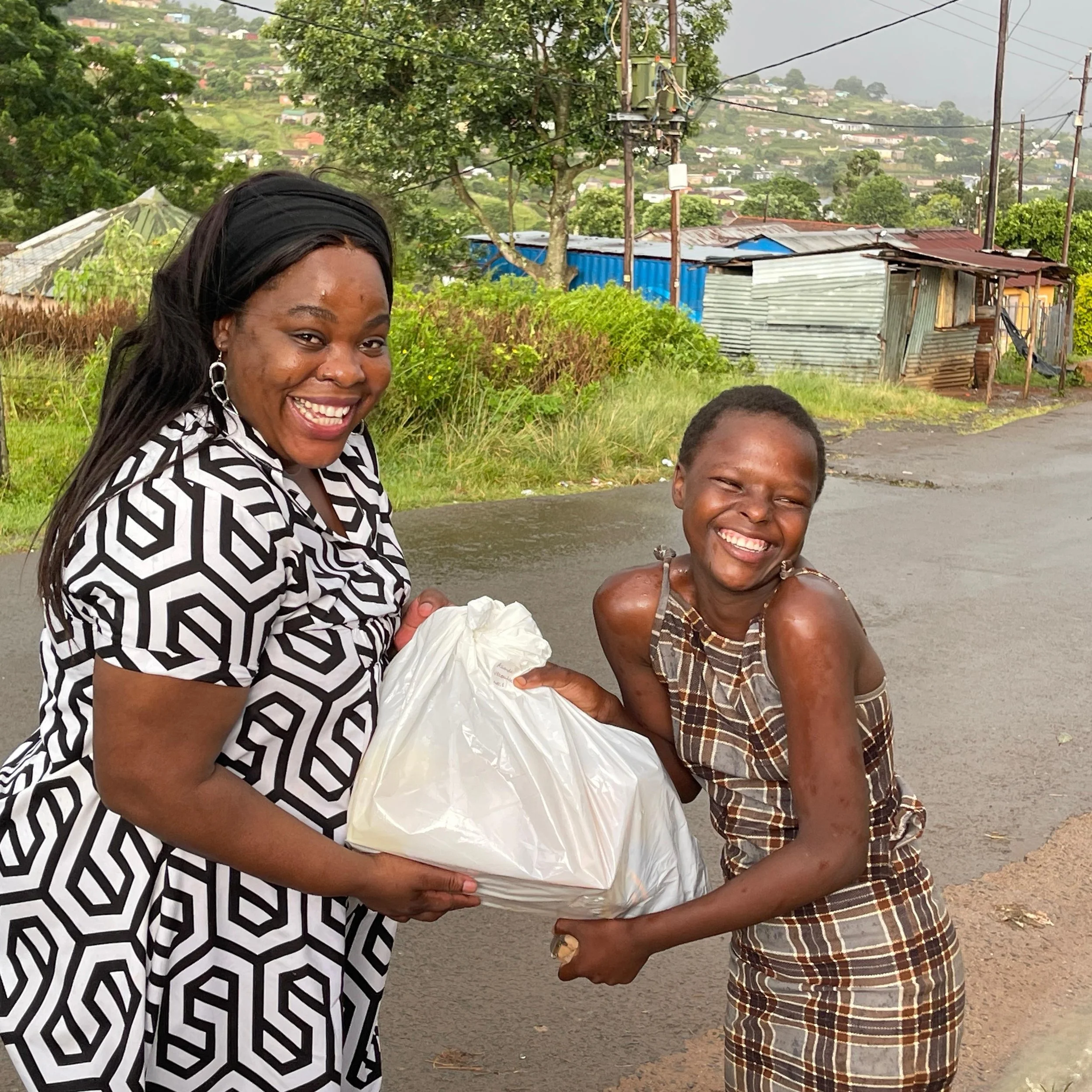 Girl receives school uniform from an E3 staff member with a huge smile