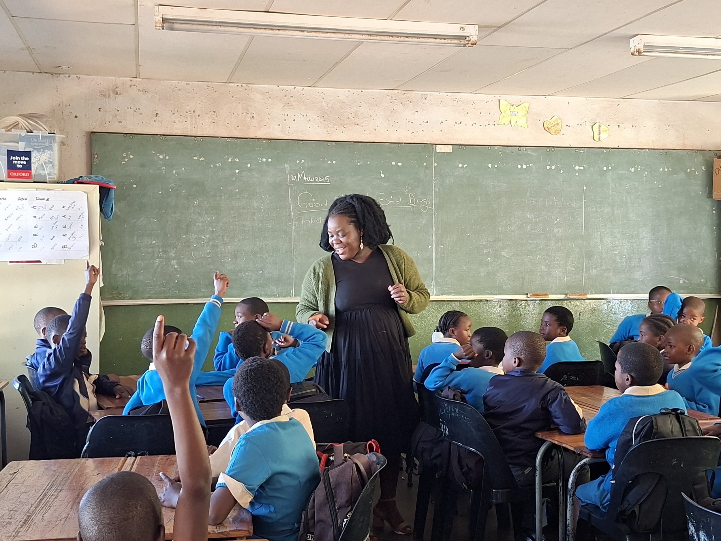 E3 staff member in a classroom leading a Life Skills class with lots of children raising their hands to answer a question