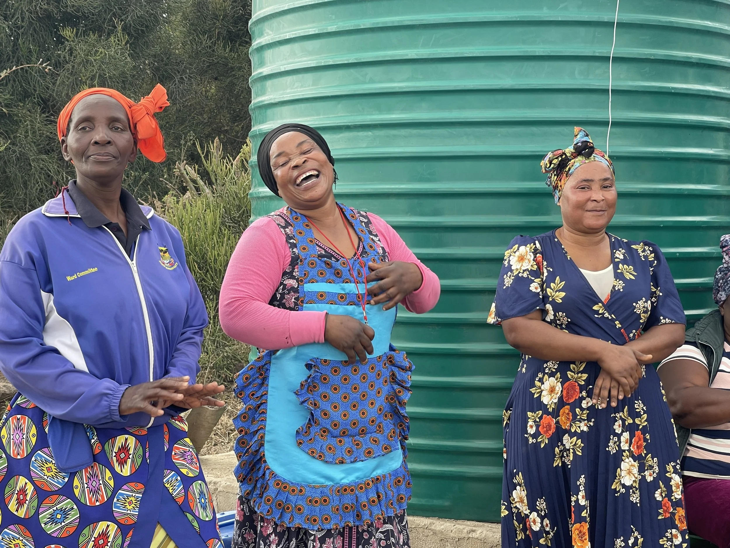 Ladies laugh and celebrate a water tank in their community
