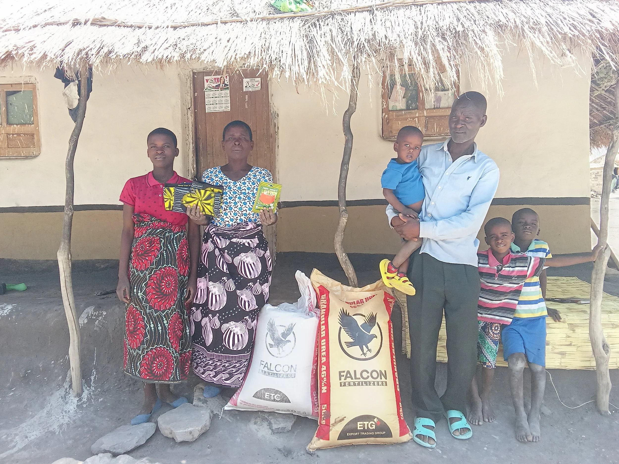 Eneleti and her family outside their mud and thatch house
