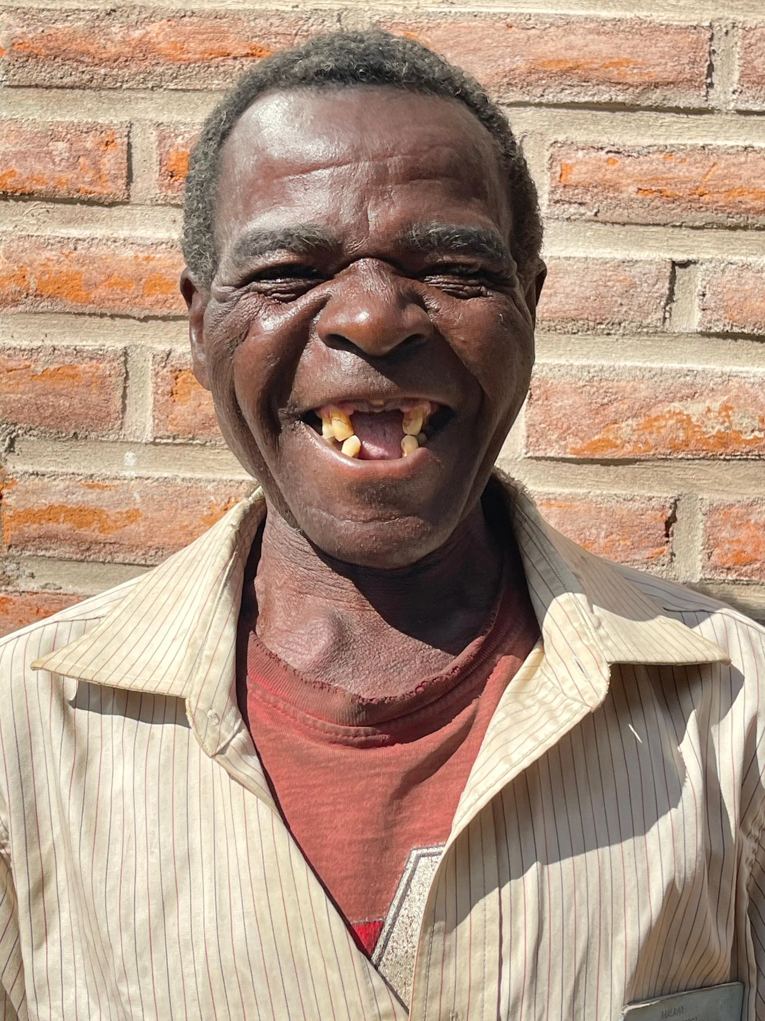 An elderly man smiles with delight about the health clinic in his community