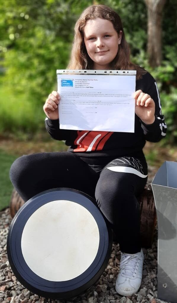 Young girl holding bodhran certificate