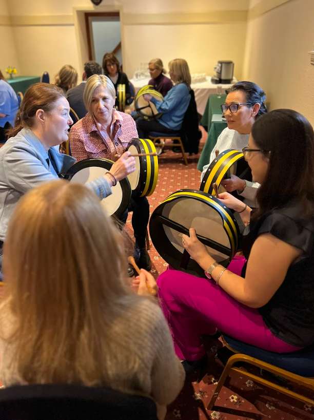A group of colleagues playing the bodhran together