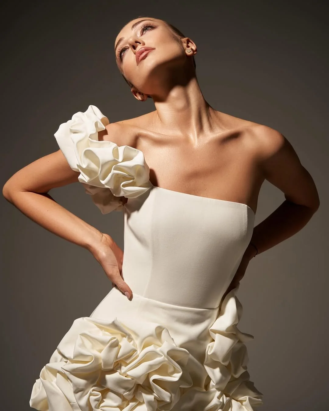 Person wearing an elegant white dress with ruffled details, posing against a plain background.