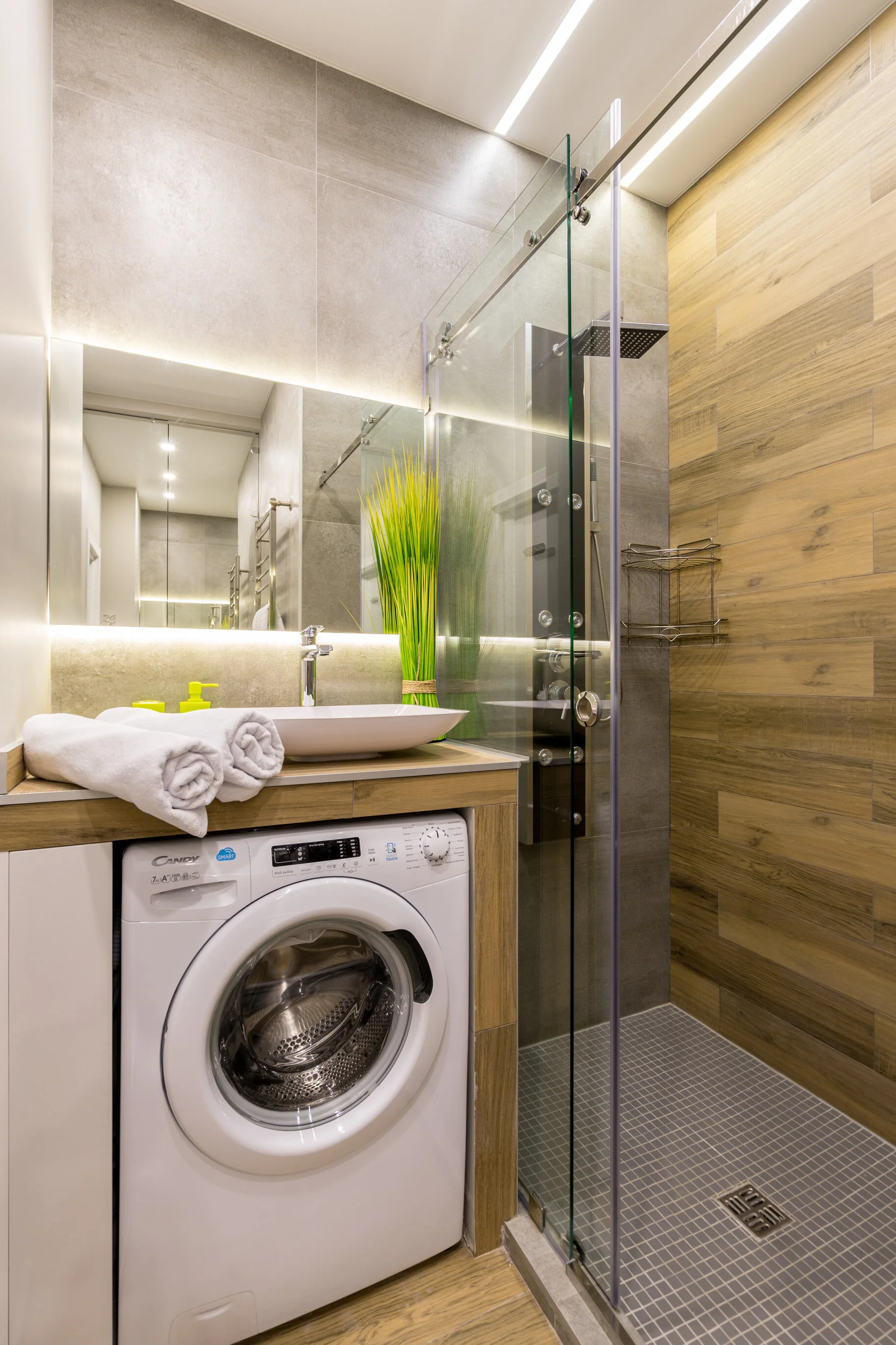 Modern bathroom with a washer, sink, mirror, and glass-enclosed shower