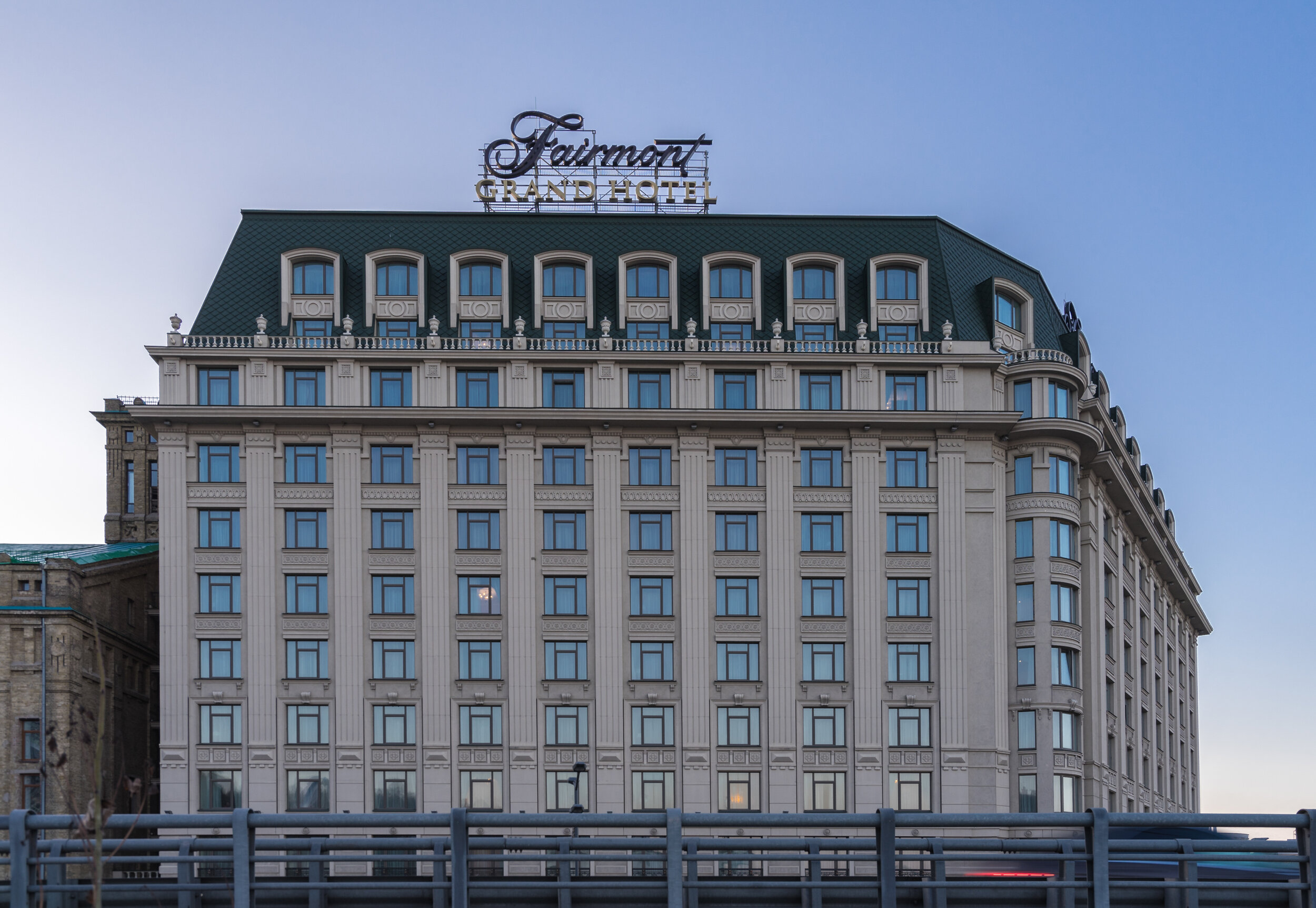 Exterior view of Fairmont Grand Hotel building with a large sign on top, featuring a classic architectural design and multiple windows, under a clear sky.
