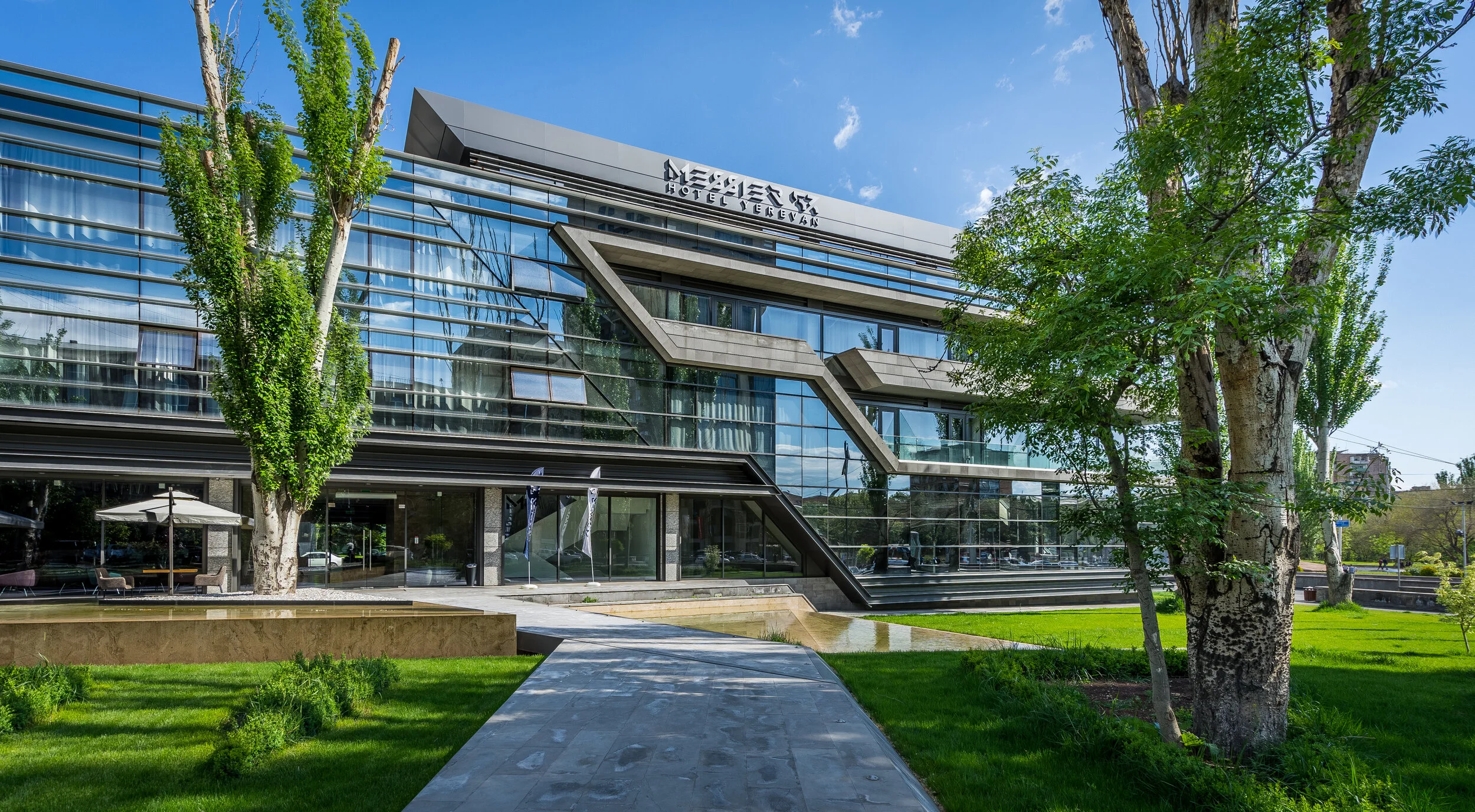 Modern hotel building with glass facade and green landscaping