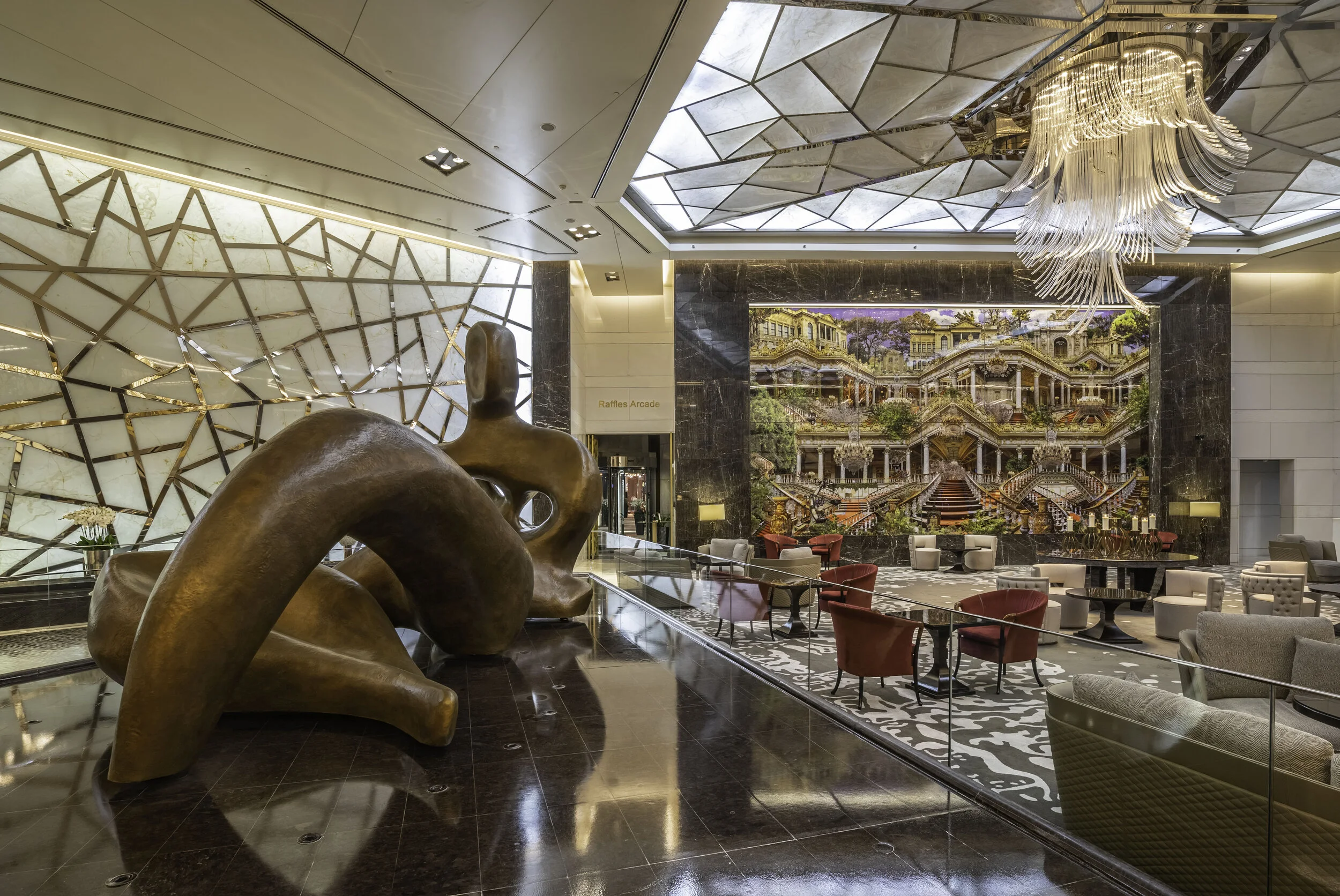 Modern hotel lobby with abstract sculpture, geometric ceiling design, colorful mural, and seating area with contemporary furniture.