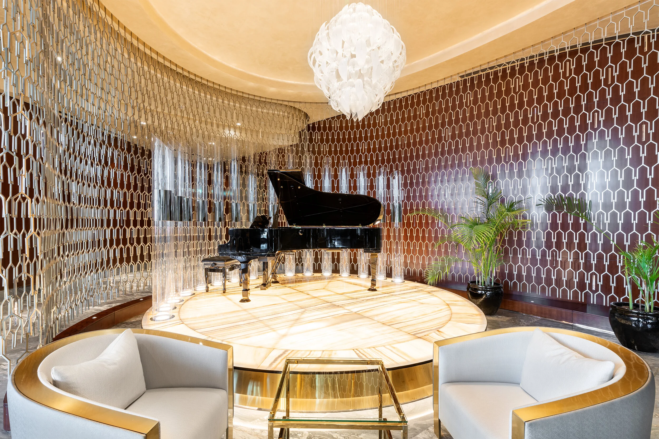 Luxurious lounge with grand piano, abstract chandelier, and modern decor, featuring curved sofas and geometric patterned walls.